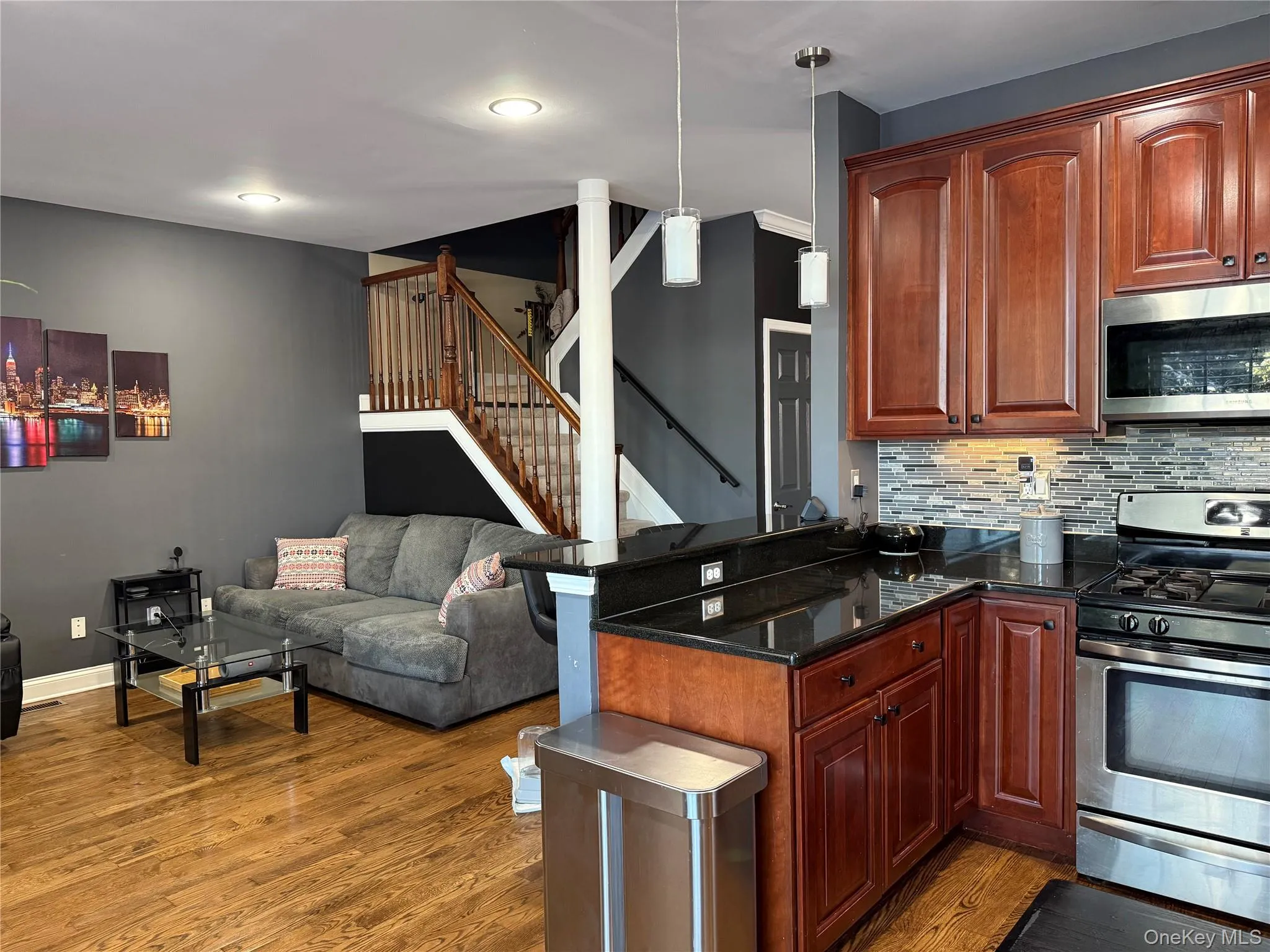 Kitchen featuring appliances with stainless steel finishes, dark stone countertops, decorative light fixtures, open floor plan, and decorative backsplash Kitchen featuring appliances with stainless steel finishes, dark stone countertops, decorative light fixtures, open floor plan, and decorative backsplash