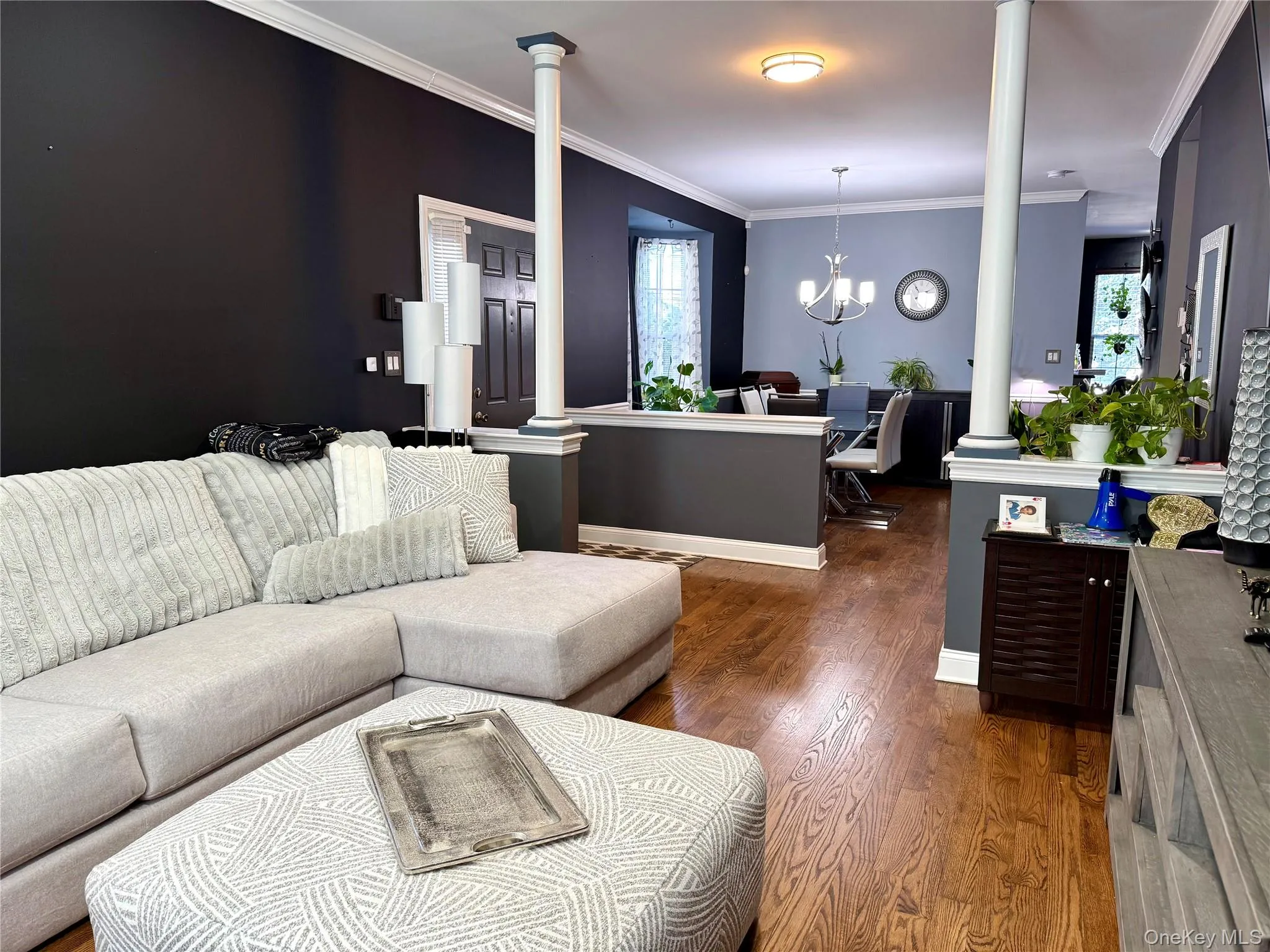 Living area with a chandelier, crown molding, wood finished floors, and decorative columns Living area with a chandelier, crown molding, wood finished floors, and decorative columns