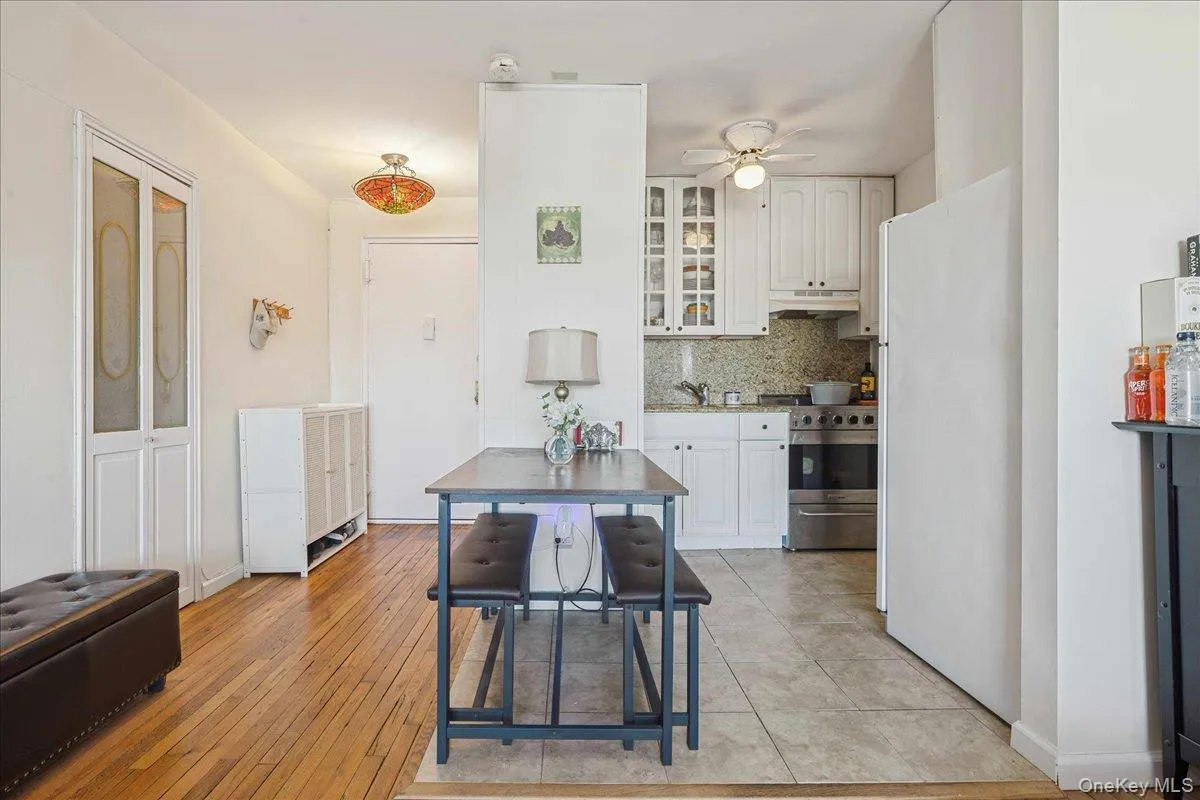 Kitchen with glass insert cabinets, freestanding refrigerator, stainless steel gas range, tasteful backsplash, and white cabinets Kitchen with glass insert cabinets, freestanding refrigerator, stainless steel gas range, tasteful backsplash, and white cabinets
