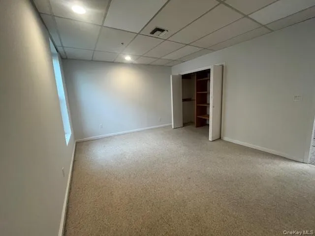 Unfurnished bedroom with a drop ceiling, a closet, and light colored carpet Unfurnished bedroom with a drop ceiling, a closet, and light colored carpet