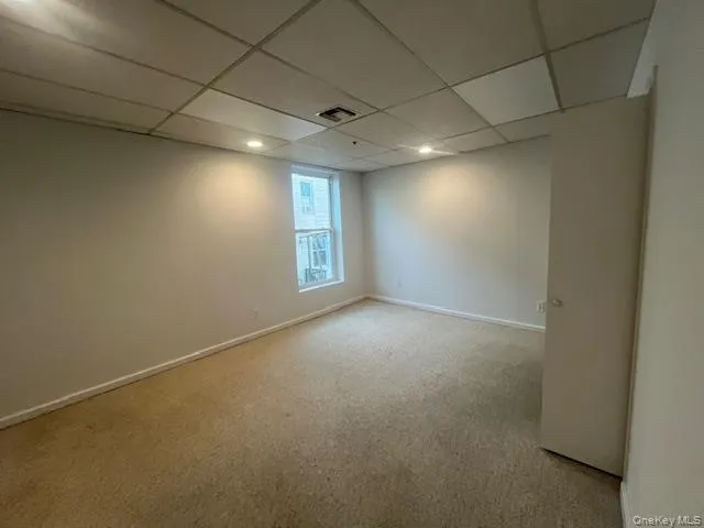 Unfurnished room with a paneled ceiling and light carpet Unfurnished room with a paneled ceiling and light carpet