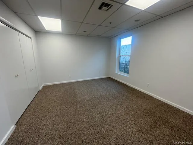 Unfurnished room with dark carpet and a paneled ceiling Unfurnished room with dark carpet and a paneled ceiling