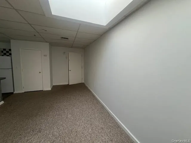 Spare room with a drop ceiling and carpet flooring Spare room with a drop ceiling and carpet flooring