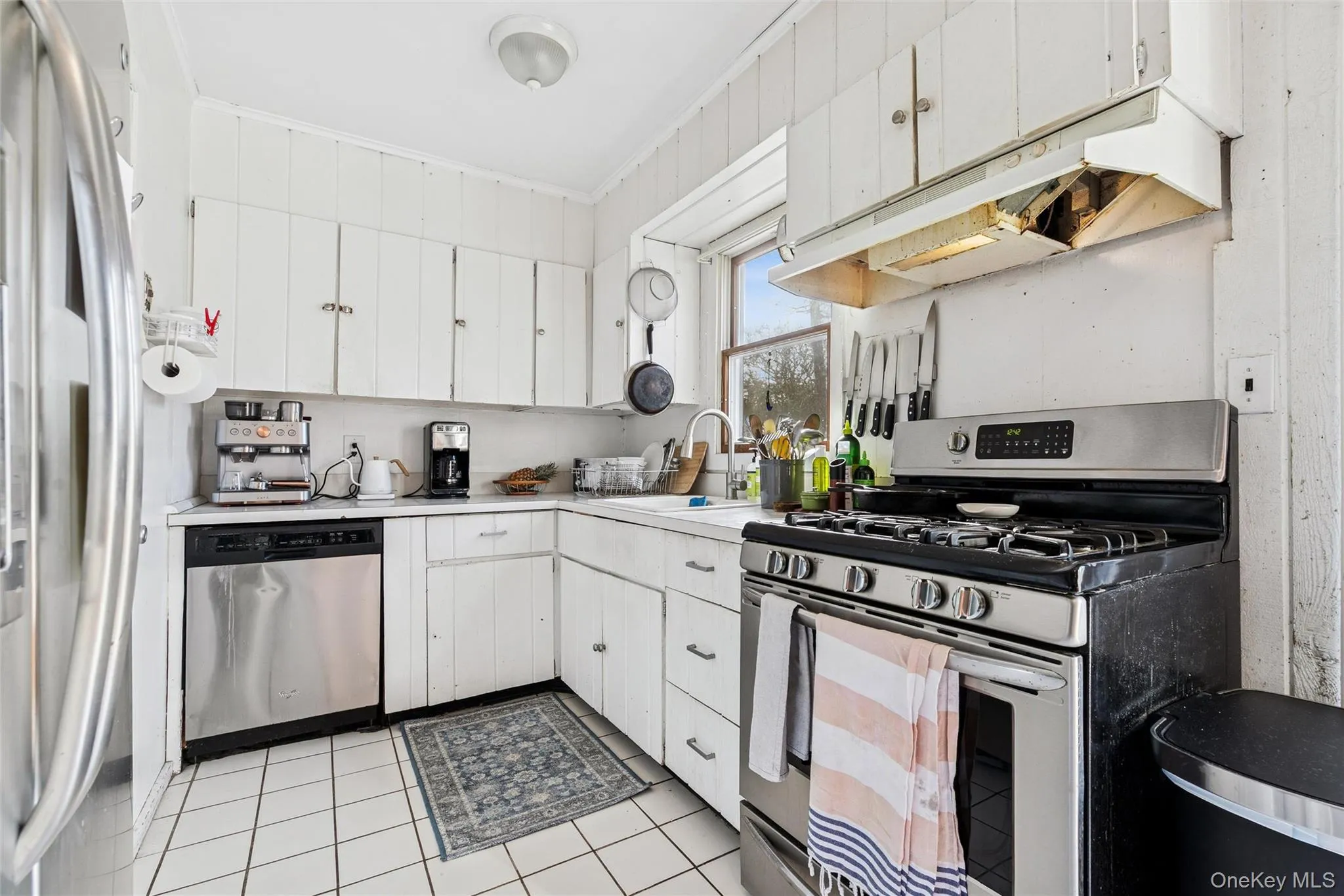 Kitchen with appliances with stainless steel finishes, white cabinetry, light countertops, and under cabinet range hood Kitchen with appliances with stainless steel finishes, white cabinetry, light countertops, and under cabinet range hood