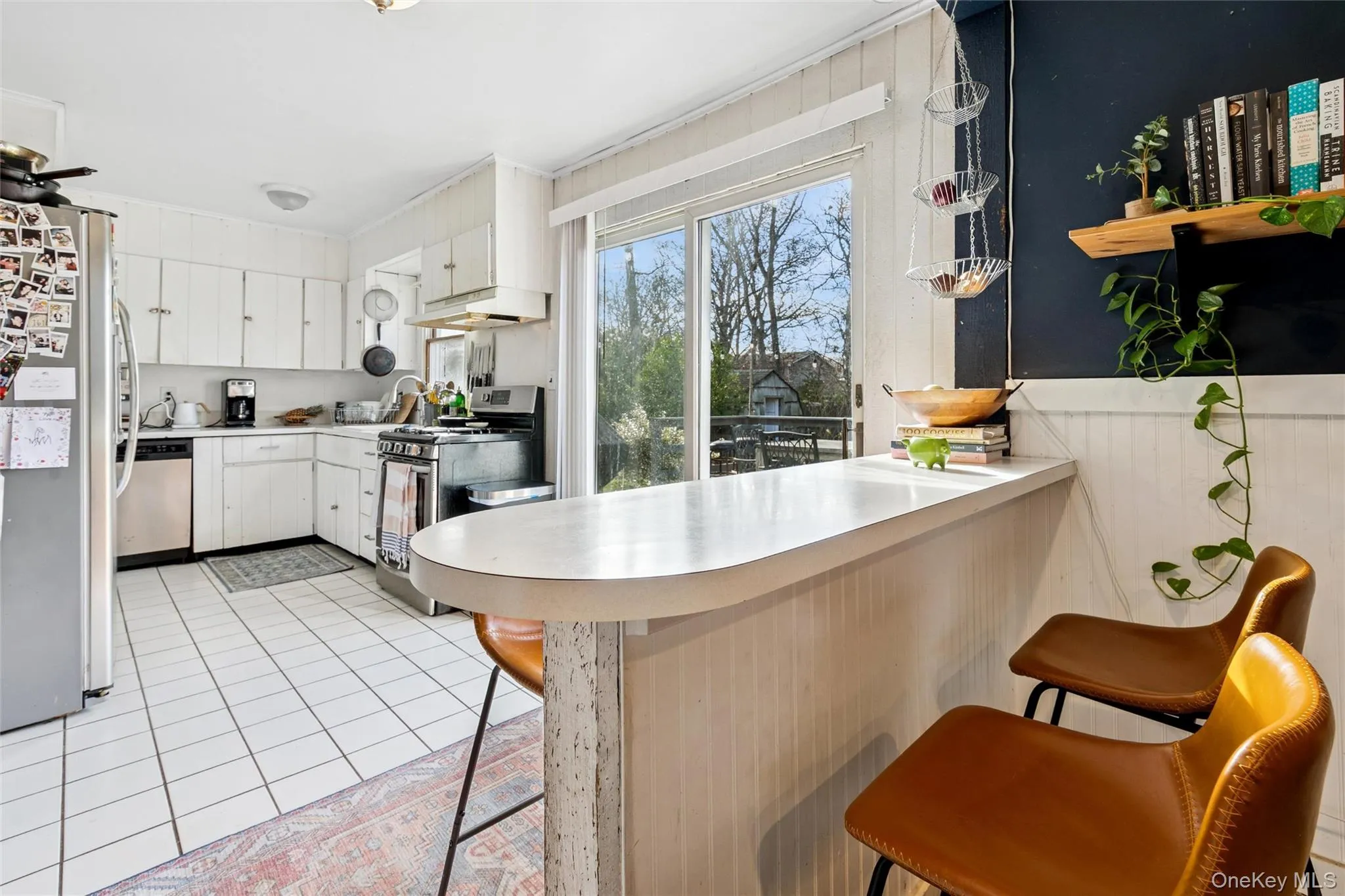 Kitchen with a kitchen breakfast bar, stainless steel appliances, white cabinets, light countertops, and a peninsula Kitchen with a kitchen breakfast bar, stainless steel appliances, white cabinets, light countertops, and a peninsula