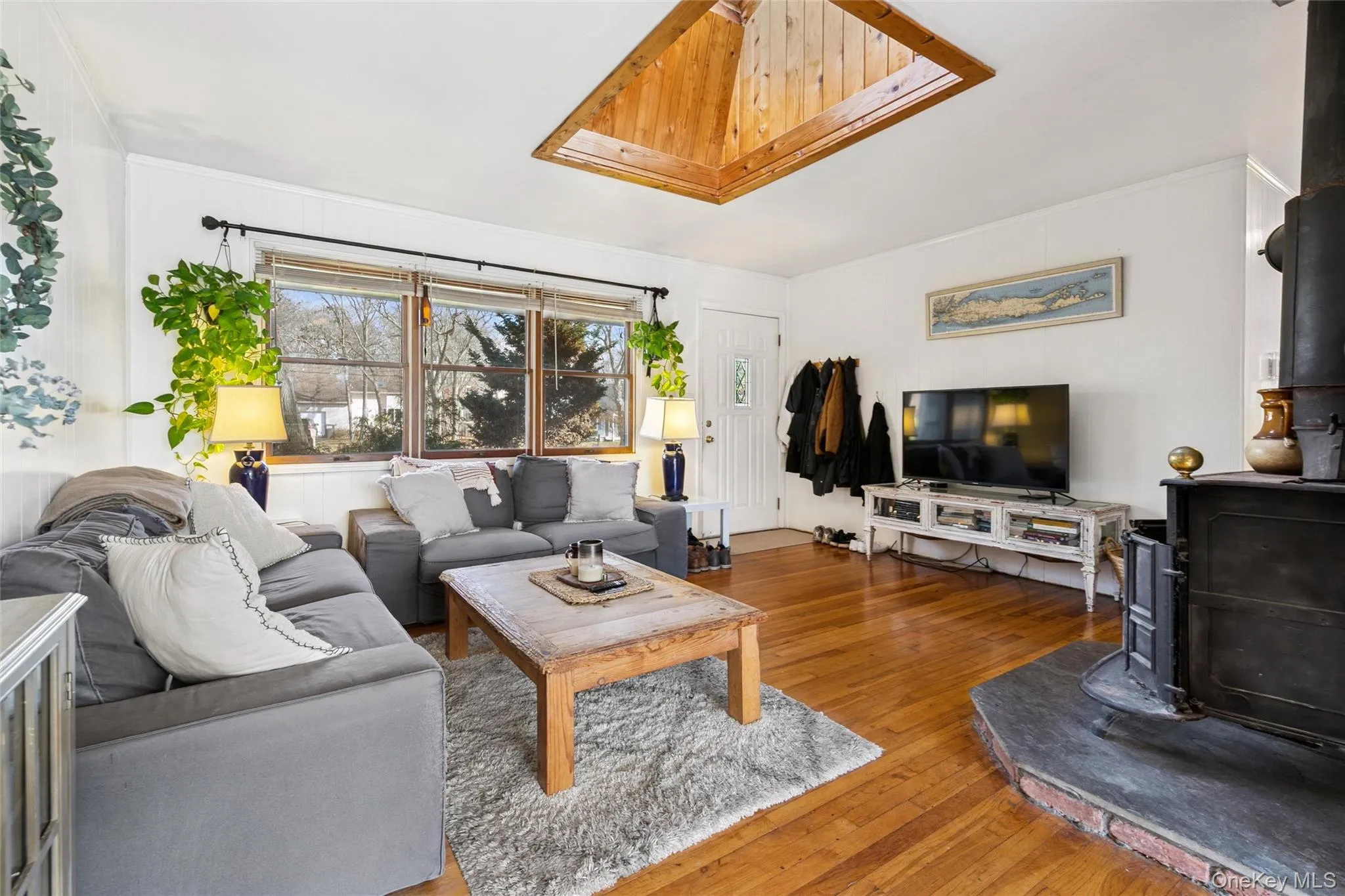 Living area with a wood stove, hardwood / wood-style flooring, and a skylight Living area with a wood stove, hardwood / wood-style flooring, and a skylight