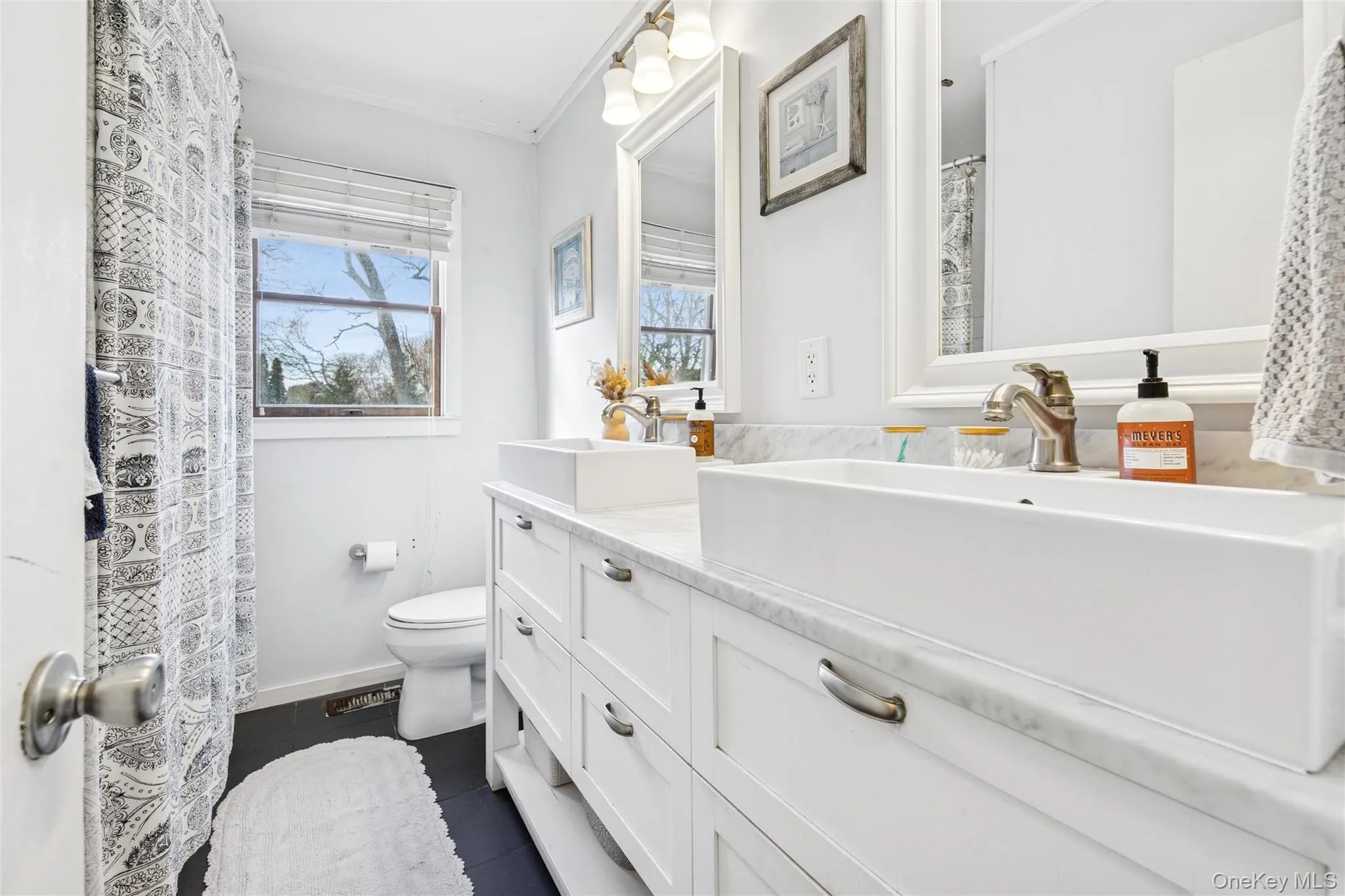 Full bathroom with a shower with curtain, double vanity, dark tile patterned flooring, and ornamental molding Full bathroom with a shower with curtain, double vanity, dark tile patterned flooring, and ornamental molding