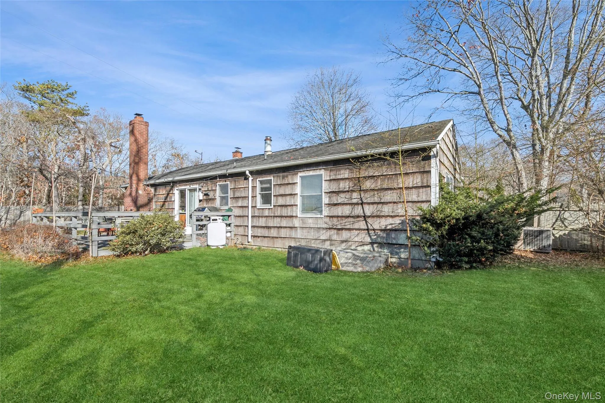 Rear view of house featuring a yard, a chimney, and a deck Rear view of house featuring a yard, a chimney, and a deck