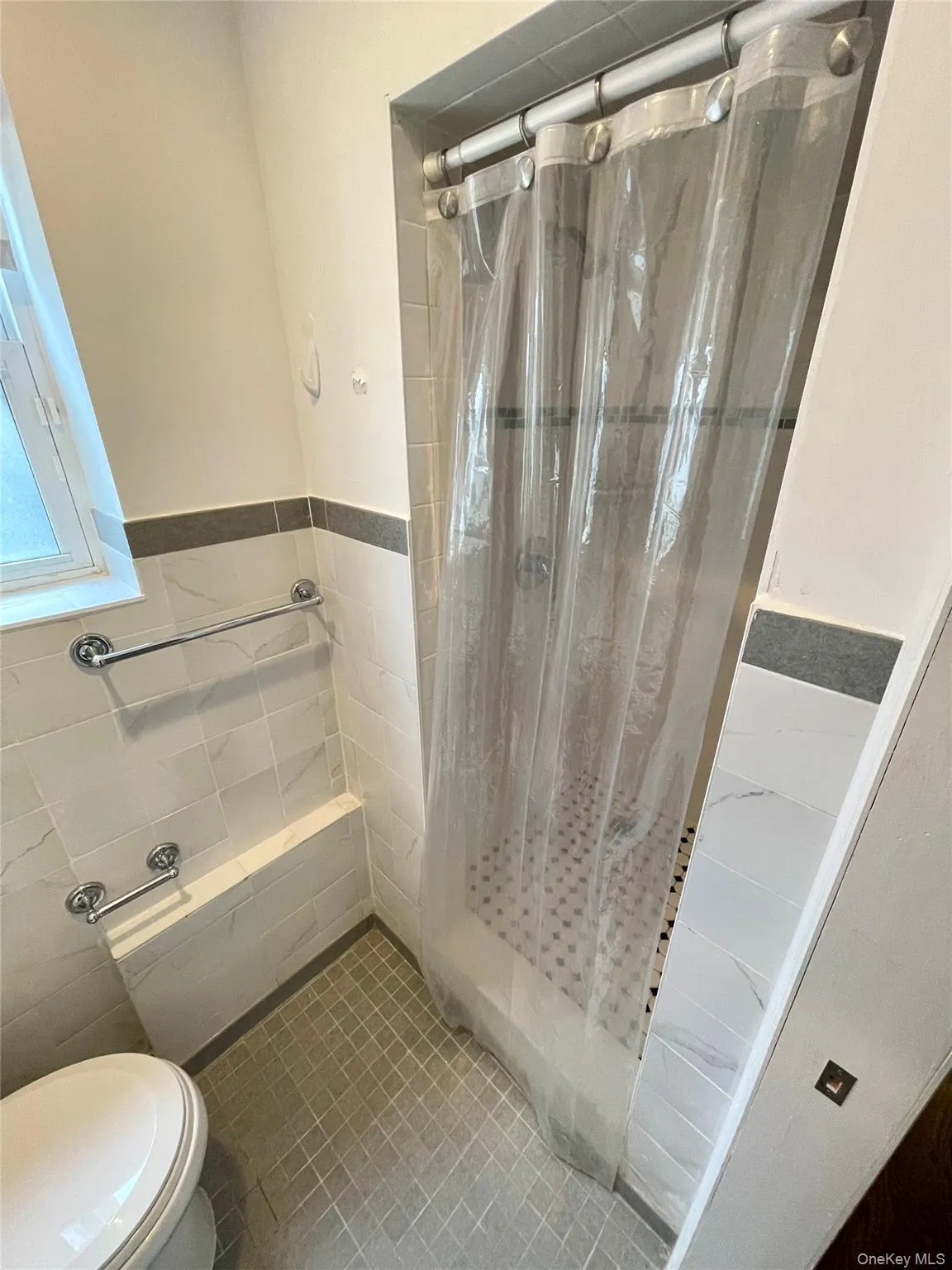 Bathroom featuring a shower stall, tile walls, and wainscoting Bathroom featuring a shower stall, tile walls, and wainscoting