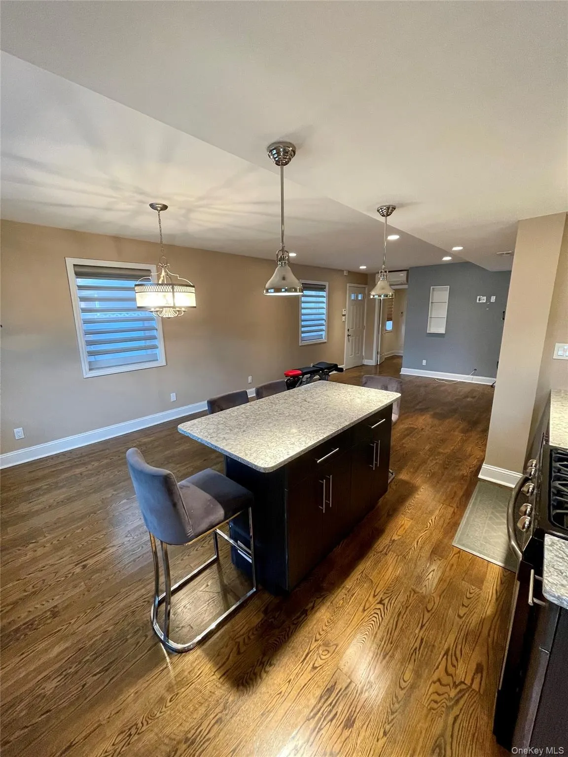 Kitchen featuring open floor plan, a kitchen island, hanging light fixtures, light stone countertops, and recessed lighting Kitchen featuring open floor plan, a kitchen island, hanging light fixtures, light stone countertops, and recessed lighting