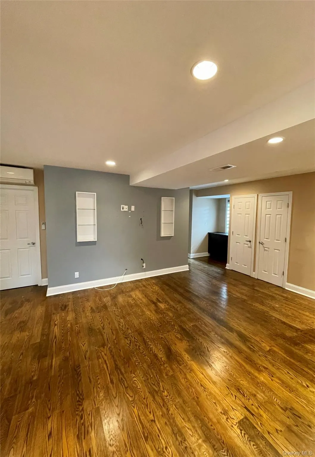 Unfurnished living room with dark wood-type flooring, an AC wall unit, and recessed lighting Unfurnished living room with dark wood-type flooring, an AC wall unit, and recessed lighting