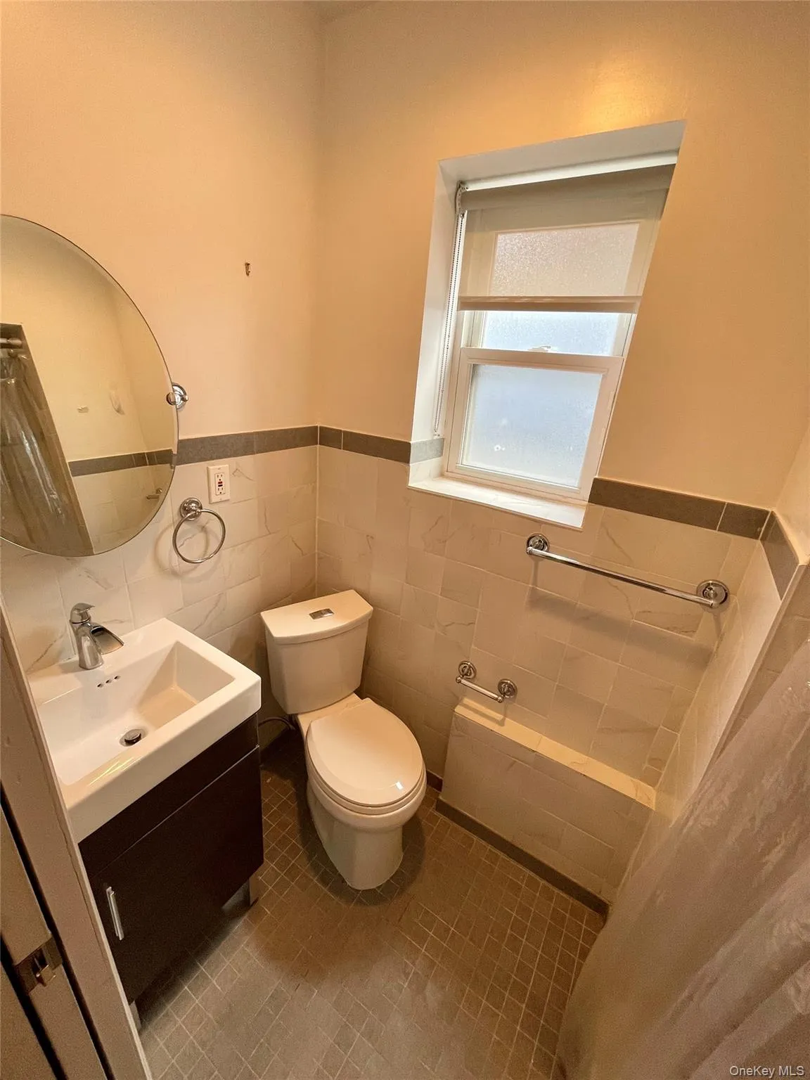 Half bathroom featuring vanity, light tile patterned floors, a wainscoted wall, and tile walls Half bathroom featuring vanity, light tile patterned floors, a wainscoted wall, and tile walls