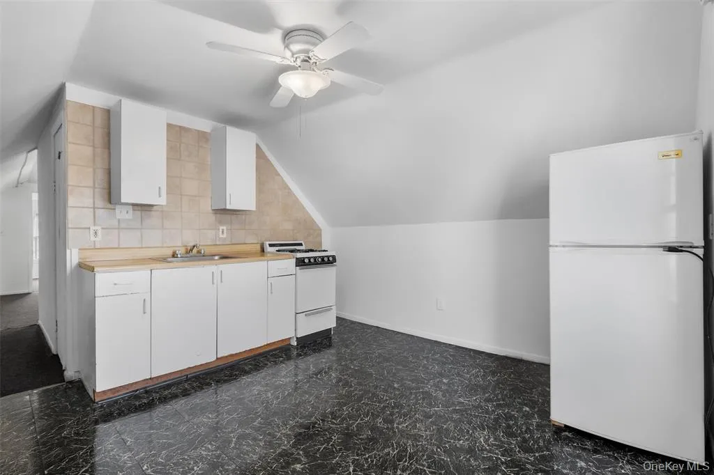 Kitchen featuring ceiling fan, sink, range, white fridge, and lofted ceiling Kitchen featuring ceiling fan, sink, range, white fridge, and lofted ceiling