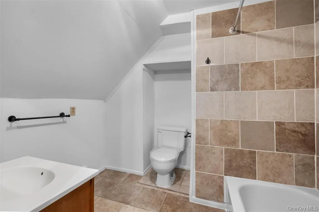 Full bathroom featuring shower / bath combination, vanity, toilet, and lofted ceiling Full bathroom featuring shower / bath combination, vanity, toilet, and lofted ceiling