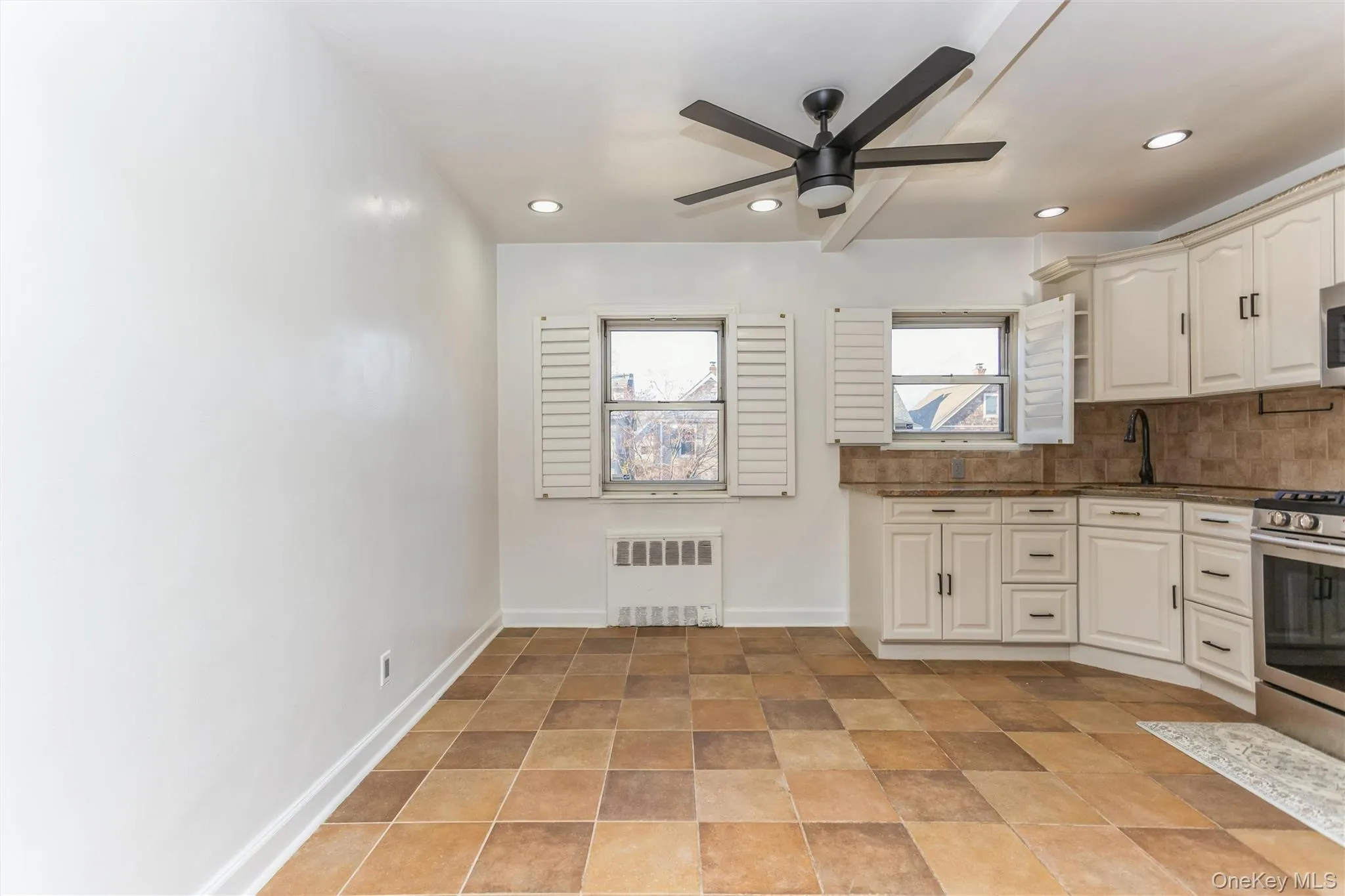 Kitchen with radiator, a ceiling fan, dark stone countertops, backsplash, and recessed lighting Kitchen with radiator, a ceiling fan, dark stone countertops, backsplash, and recessed lighting