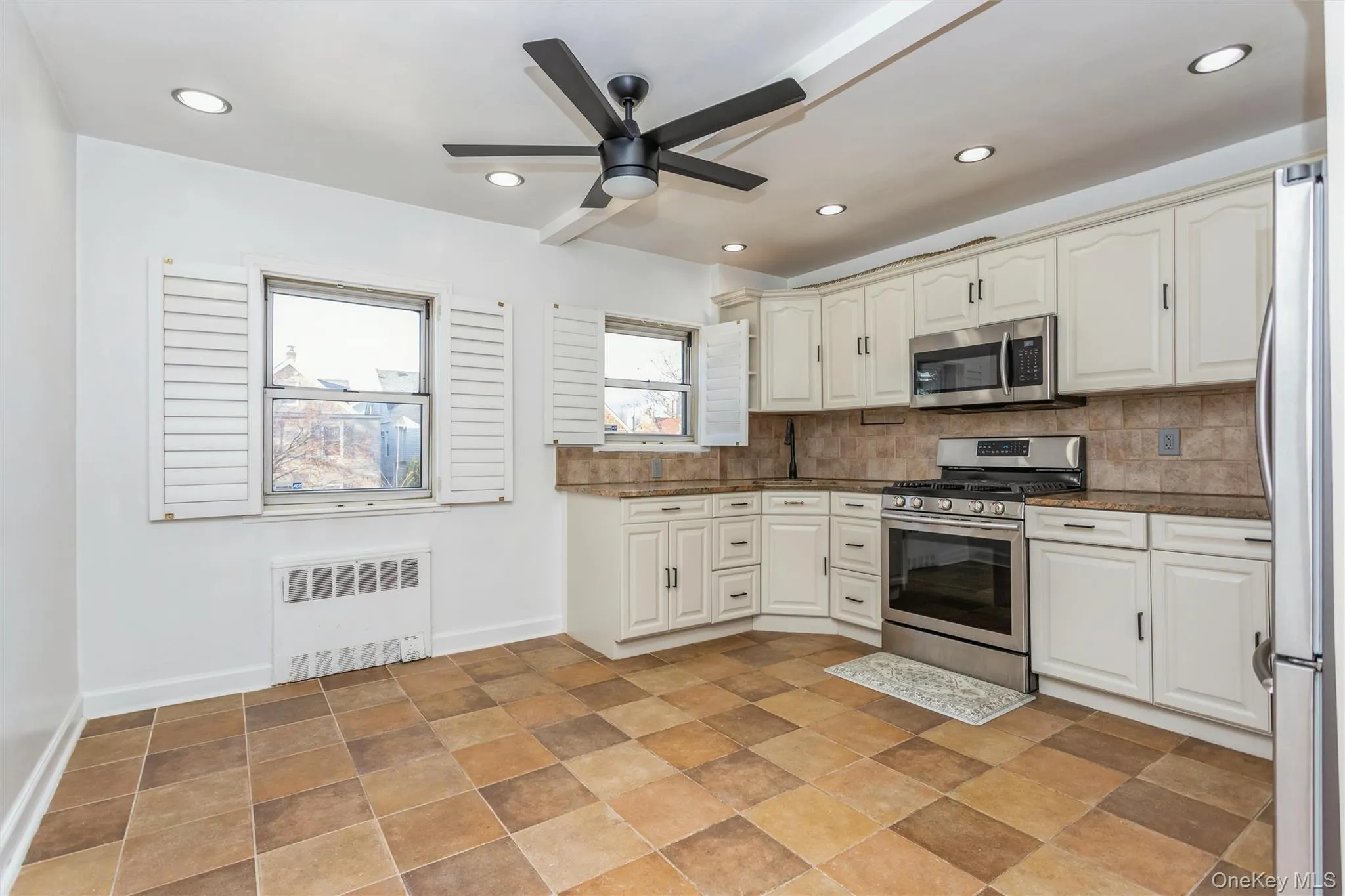 Kitchen featuring stainless steel appliances, radiator heating unit, recessed lighting, backsplash, and a ceiling fan Kitchen featuring stainless steel appliances, radiator heating unit, recessed lighting, backsplash, and a ceiling fan