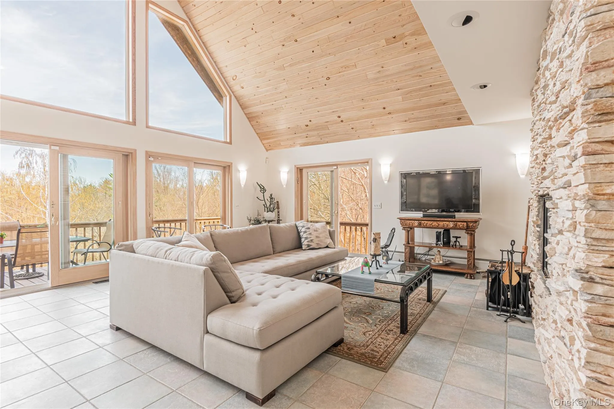 Living area with high vaulted ceiling, wood ceiling, and light tile patterned flooring Living area with high vaulted ceiling, wood ceiling, and light tile patterned flooring