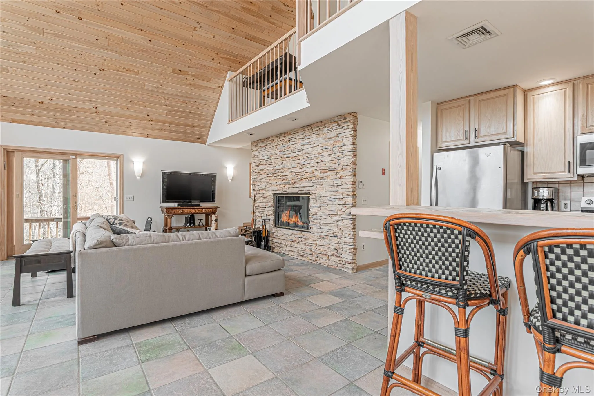 Living room with high vaulted ceiling, wood ceiling, and a stone fireplace Living room with high vaulted ceiling, wood ceiling, and a stone fireplace