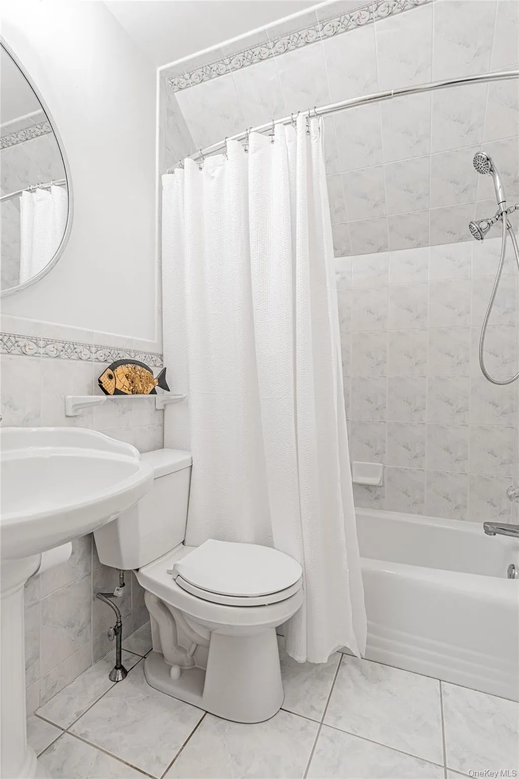 Full bathroom featuring shower / tub combo with curtain, tile walls, and a wainscoted wall Full bathroom featuring shower / tub combo with curtain, tile walls, and a wainscoted wall