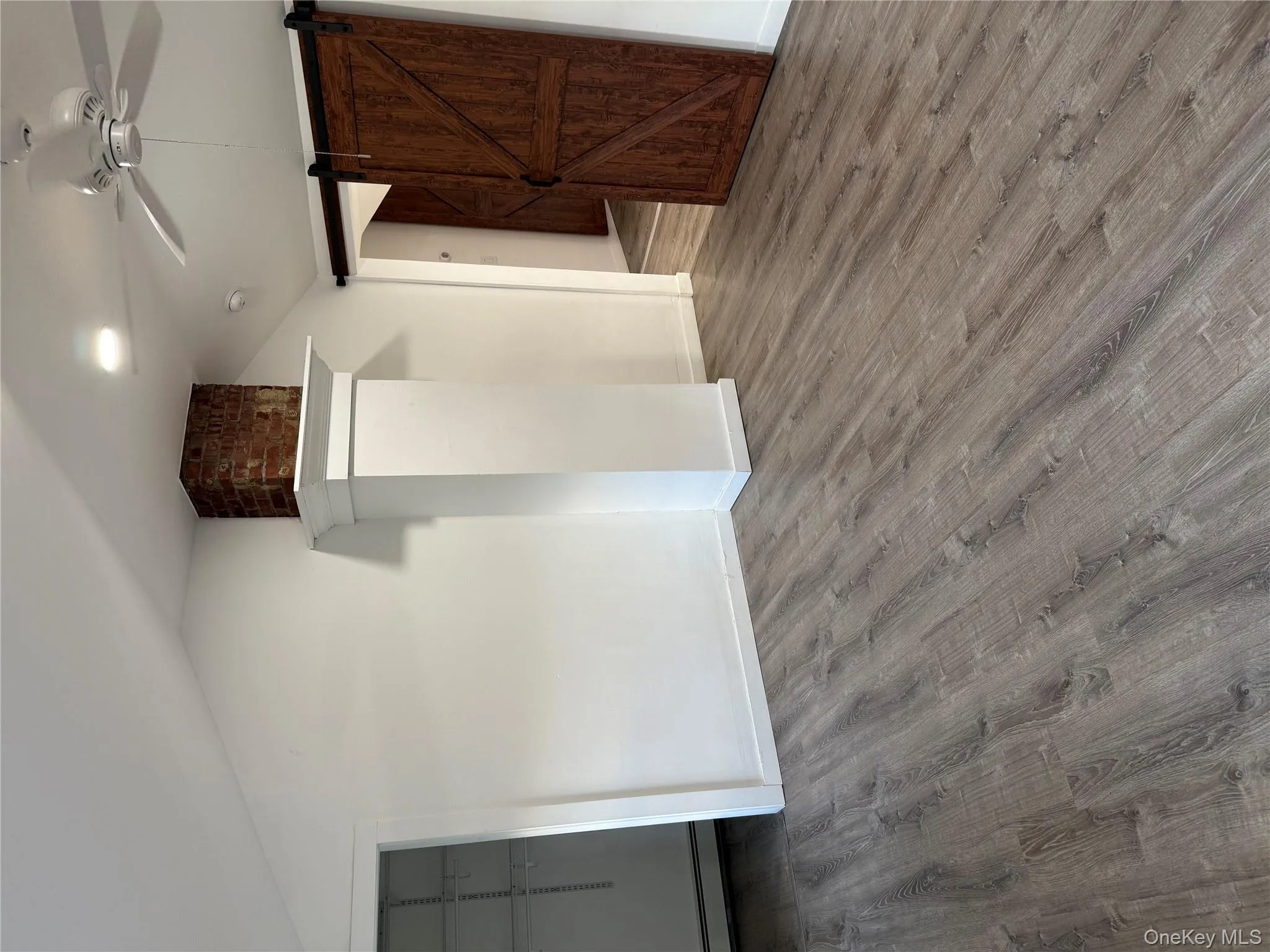 Unfurnished bedroom featuring a barn door, vaulted ceiling, a ceiling fan, wood finished floors, and a baseboard heating unit Unfurnished bedroom featuring a barn door, vaulted ceiling, a ceiling fan, wood finished floors, and a baseboard heating unit