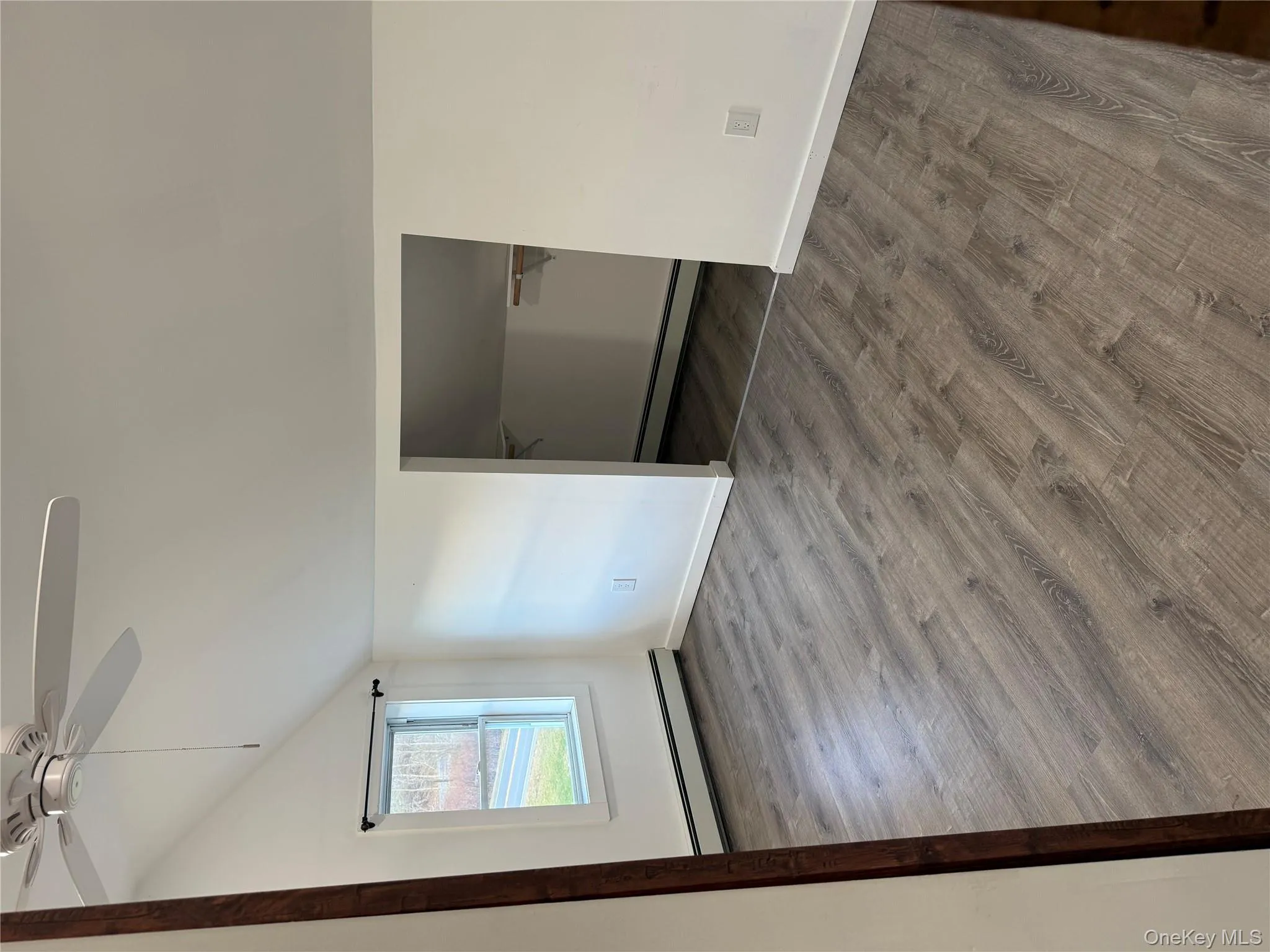 Unfurnished bedroom featuring lofted ceiling, a baseboard heating unit, wood finished floors, ceiling fan, and a spacious closet Unfurnished bedroom featuring lofted ceiling, a baseboard heating unit, wood finished floors, ceiling fan, and a spacious closet