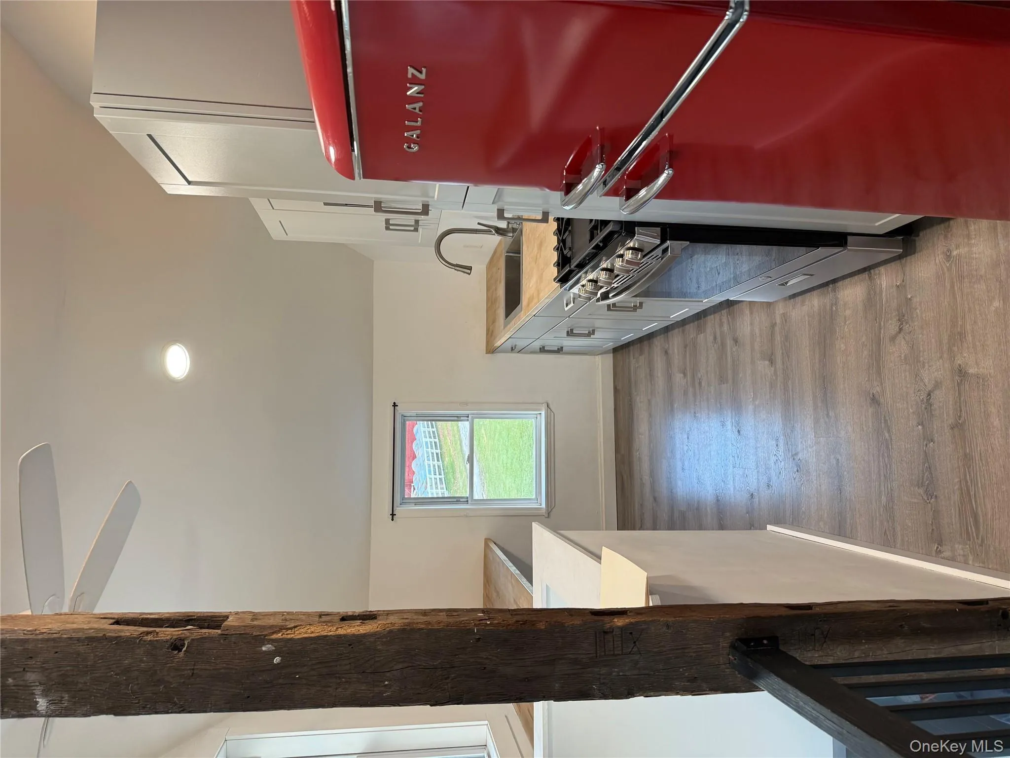 Kitchen featuring stainless steel fridge, light countertops, vaulted ceiling, range, and light wood-type flooring Kitchen featuring stainless steel fridge, light countertops, vaulted ceiling, range, and light wood-type flooring