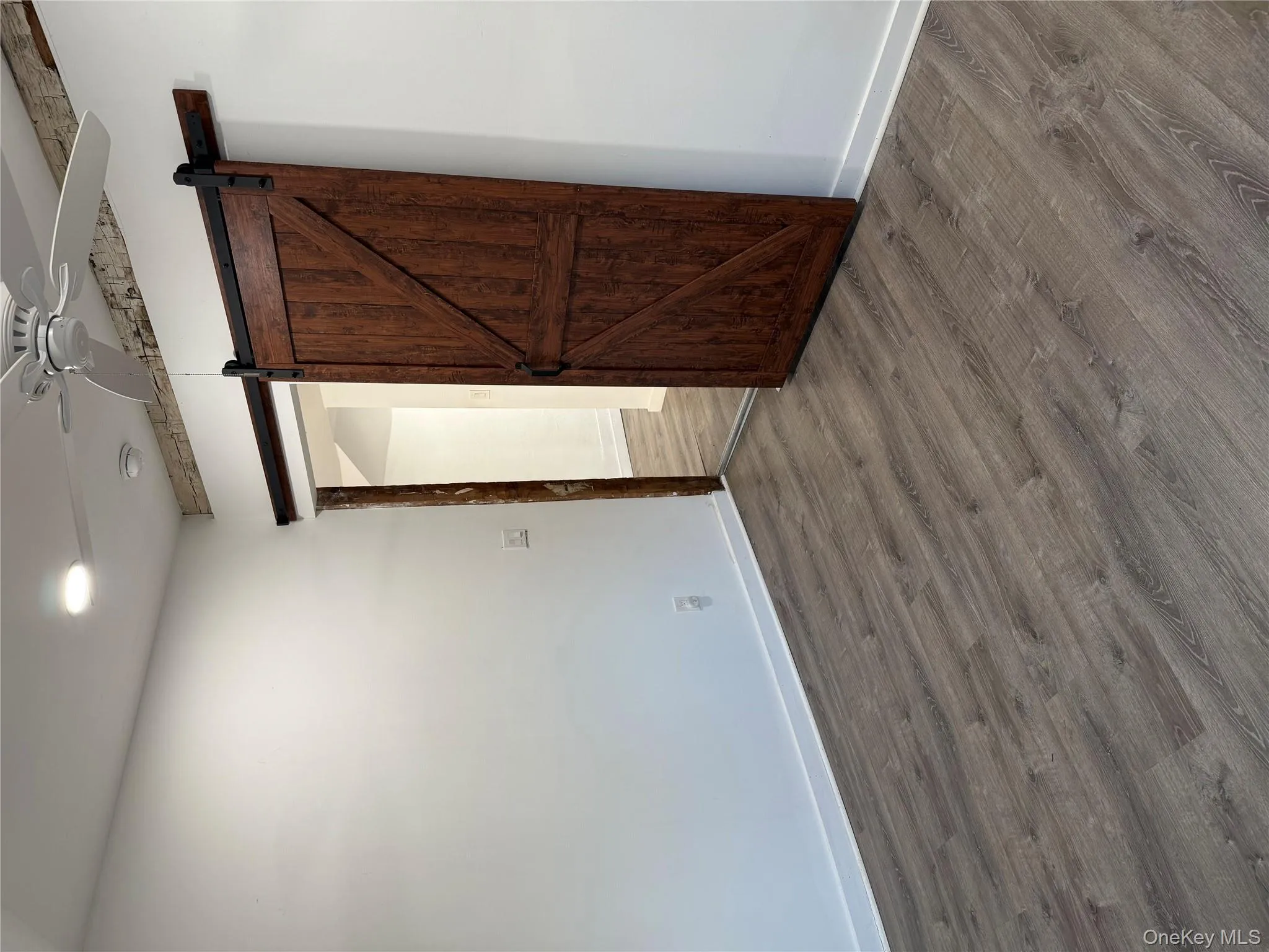 Unfurnished bedroom with a ceiling fan, dark wood-style flooring, a barn door, and recessed lighting Unfurnished bedroom with a ceiling fan, dark wood-style flooring, a barn door, and recessed lighting