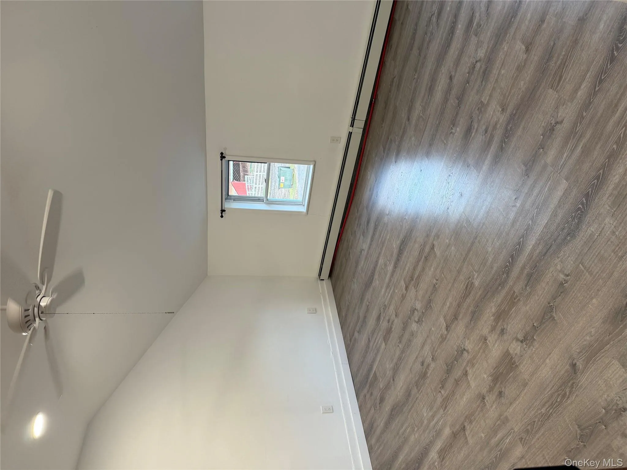 Empty room featuring lofted ceiling, a baseboard heating unit, wood finished floors, and a ceiling fan Empty room featuring lofted ceiling, a baseboard heating unit, wood finished floors, and a ceiling fan