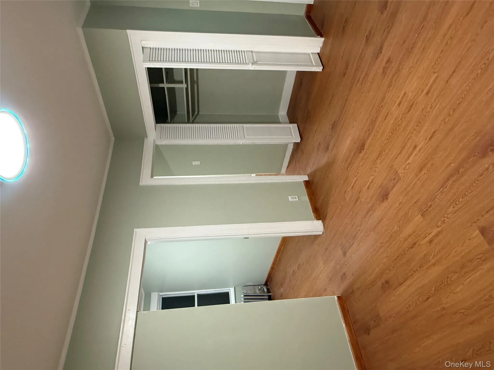 Unfurnished bedroom featuring radiator heating unit, light wood-style flooring, a closet, and ornamental molding Unfurnished bedroom featuring radiator heating unit, light wood-style flooring, a closet, and ornamental molding