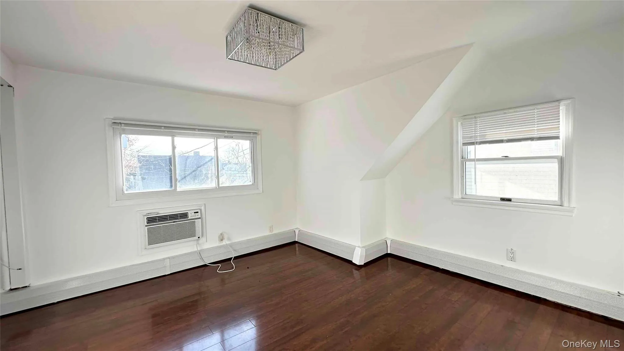Additional living space with dark wood-type flooring and a wall mounted AC Additional living space with dark wood-type flooring and a wall mounted AC