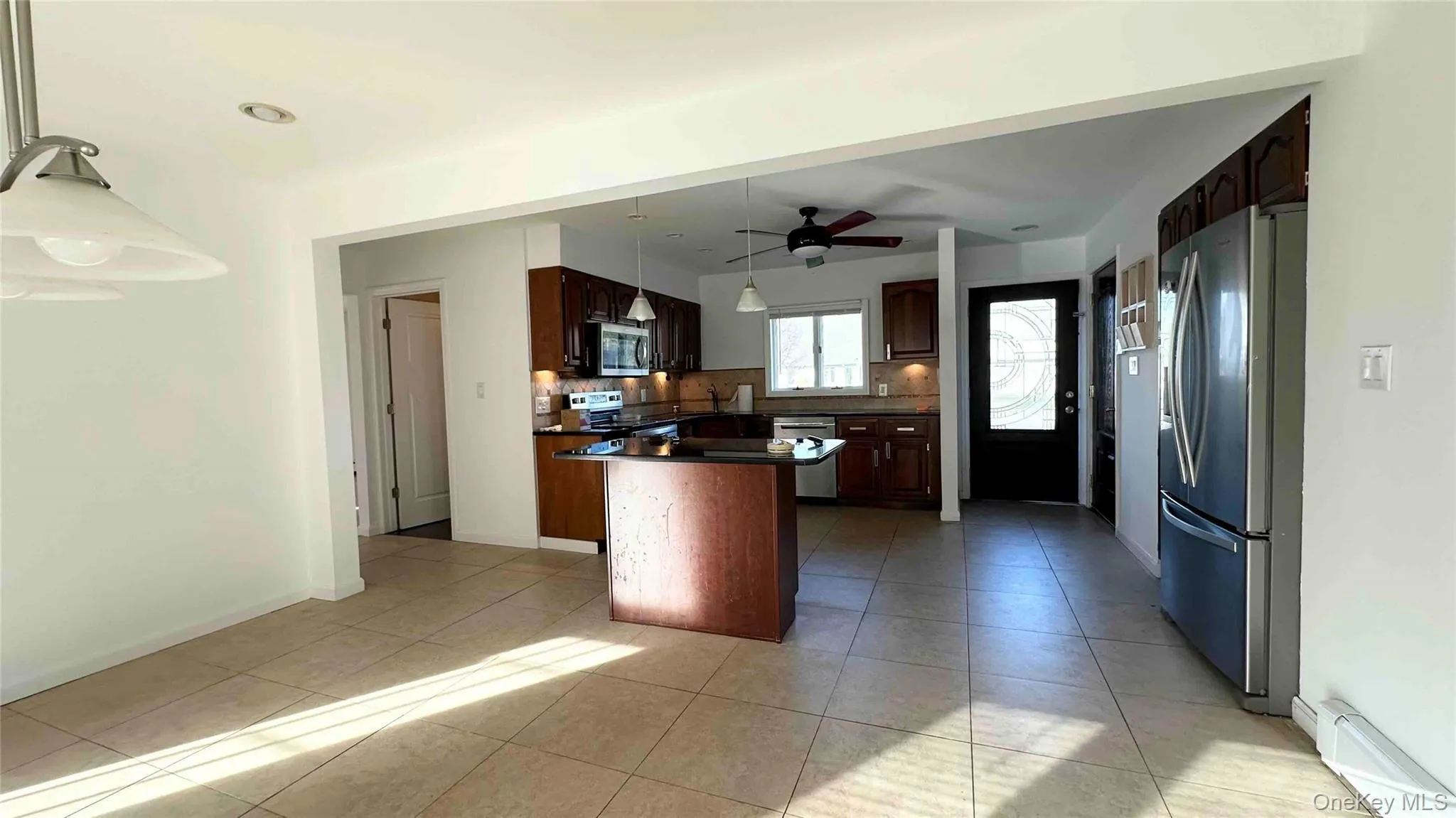 Kitchen featuring appliances with stainless steel finishes, hanging light fixtures, a baseboard heating unit, dark brown cabinetry, and tasteful backsplash Kitchen featuring appliances with stainless steel finishes, hanging light fixtures, a baseboard heating unit, dark brown cabinetry, and tasteful backsplash
