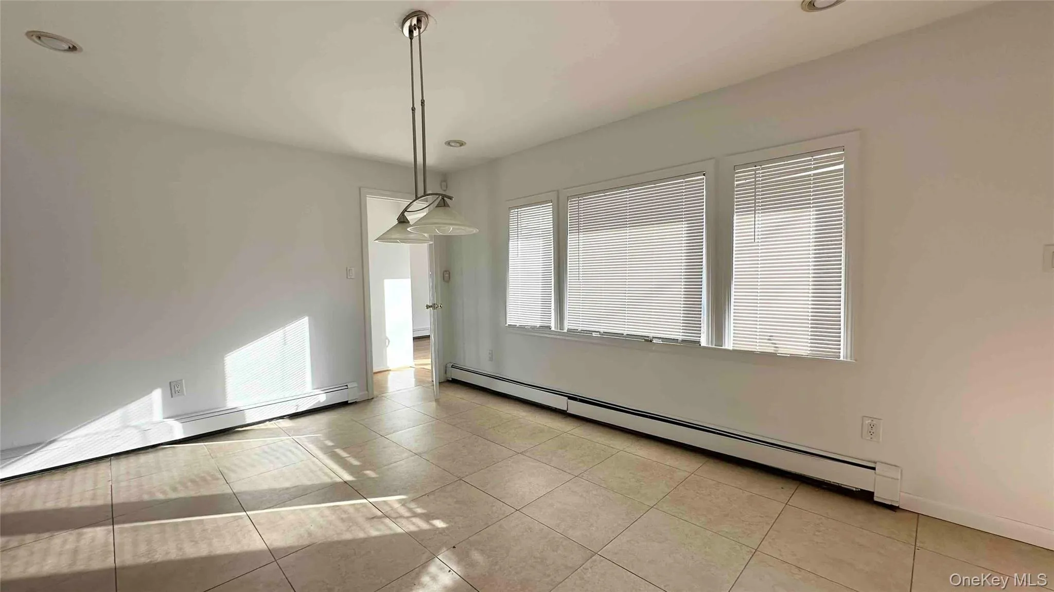 Unfurnished dining area with a baseboard radiator, baseboard heating, light tile patterned floors, and recessed lighting Unfurnished dining area with a baseboard radiator, baseboard heating, light tile patterned floors, and recessed lighting