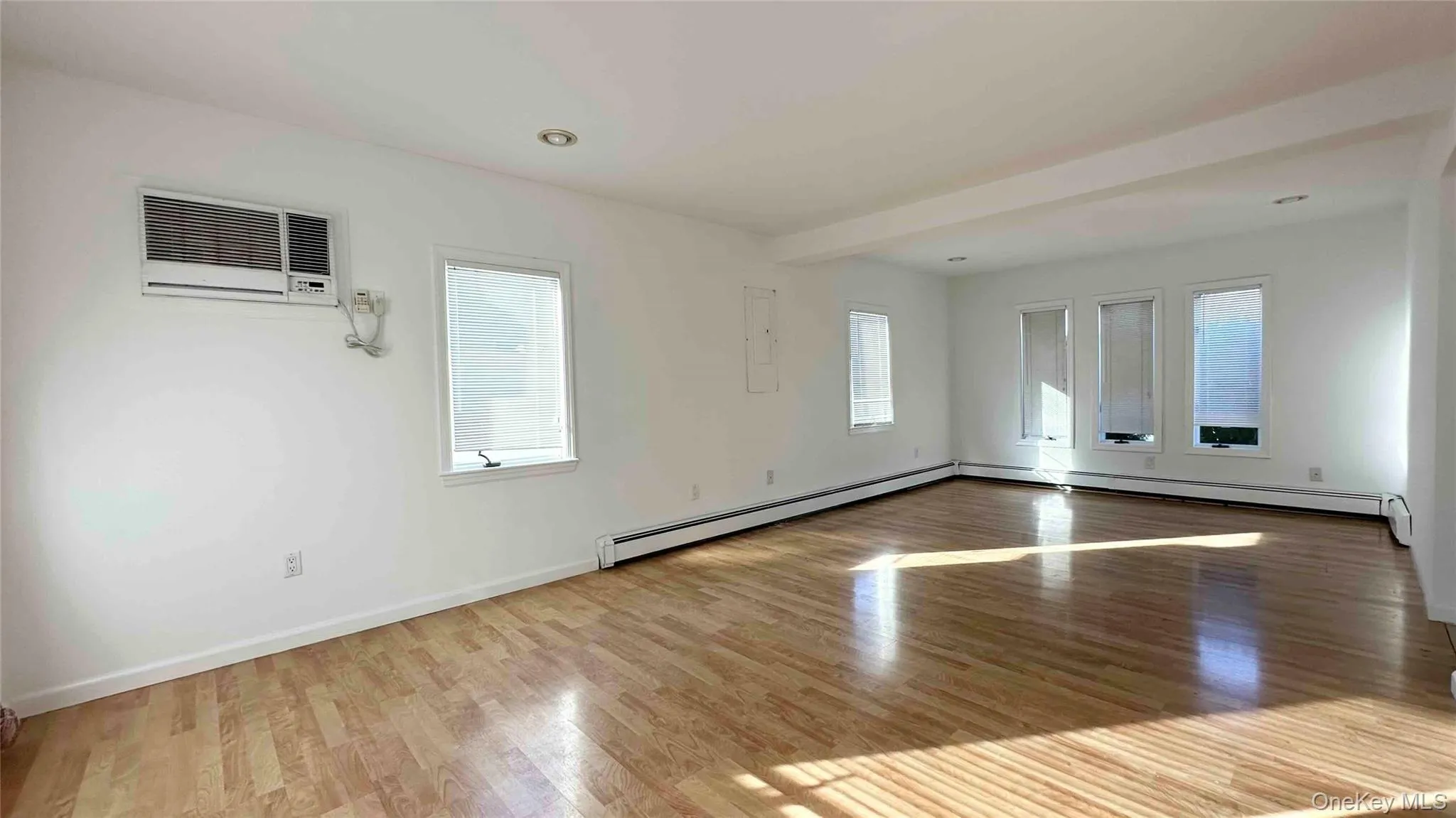 Spare room featuring wood finished floors, baseboard heating, a wall mounted air conditioner, and recessed lighting Spare room featuring wood finished floors, baseboard heating, a wall mounted air conditioner, and recessed lighting