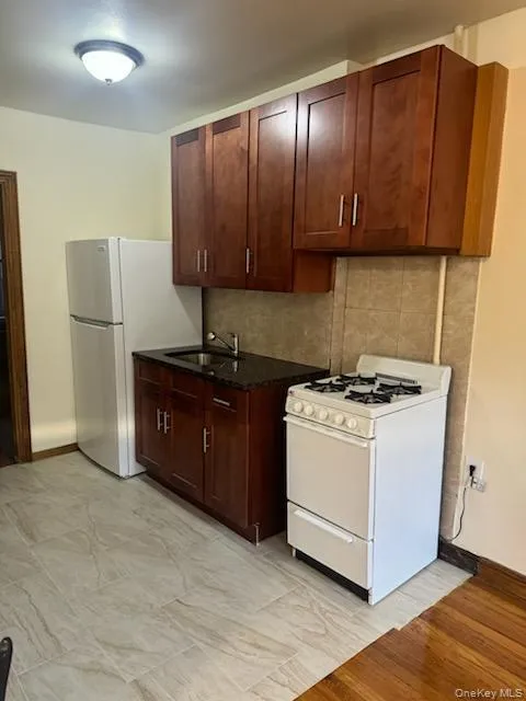Kitchen featuring white appliances, tasteful backsplash, and dark stone countertops Kitchen featuring white appliances, tasteful backsplash, and dark stone countertops
