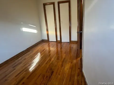 Unfurnished bedroom with dark wood finished floors and baseboards Unfurnished bedroom with dark wood finished floors and baseboards