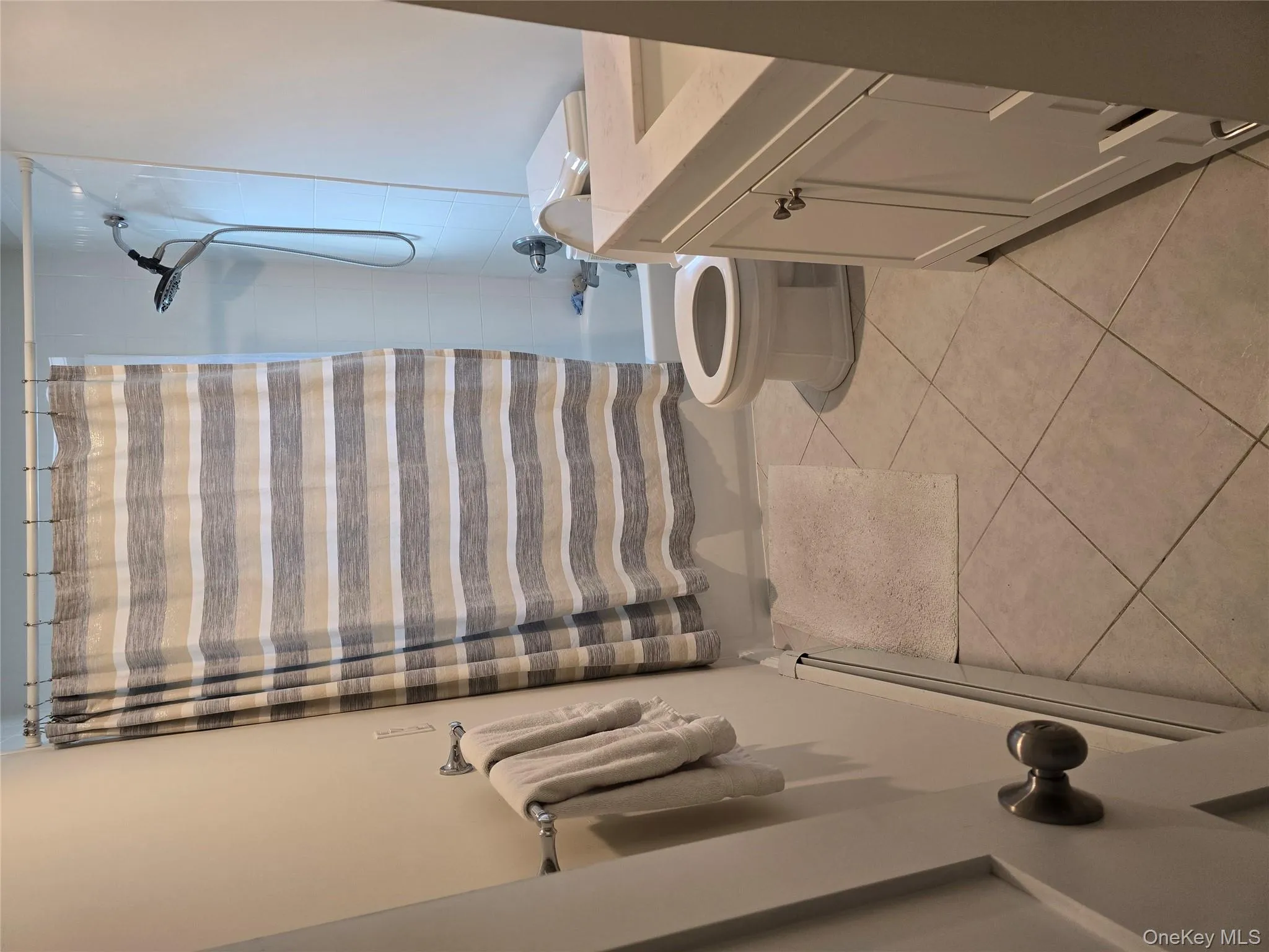 Full bathroom with vanity, shower / bath combo, a baseboard radiator, and light tile patterned flooring Full bathroom with vanity, shower / bath combo, a baseboard radiator, and light tile patterned flooring