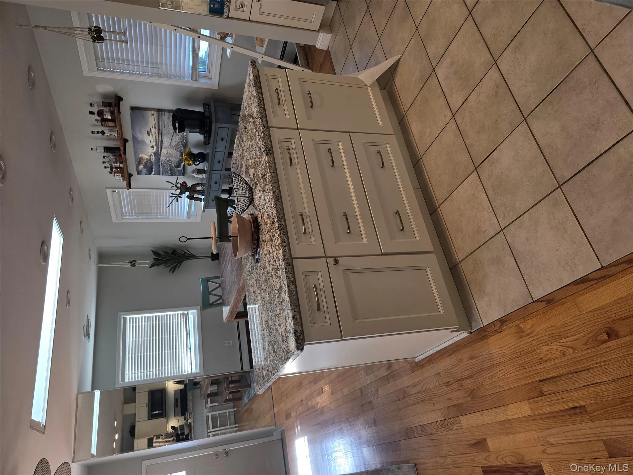 Kitchen with light stone countertops, a skylight, a center island, white cabinetry, and light wood-style flooring Kitchen with light stone countertops, a skylight, a center island, white cabinetry, and light wood-style flooring