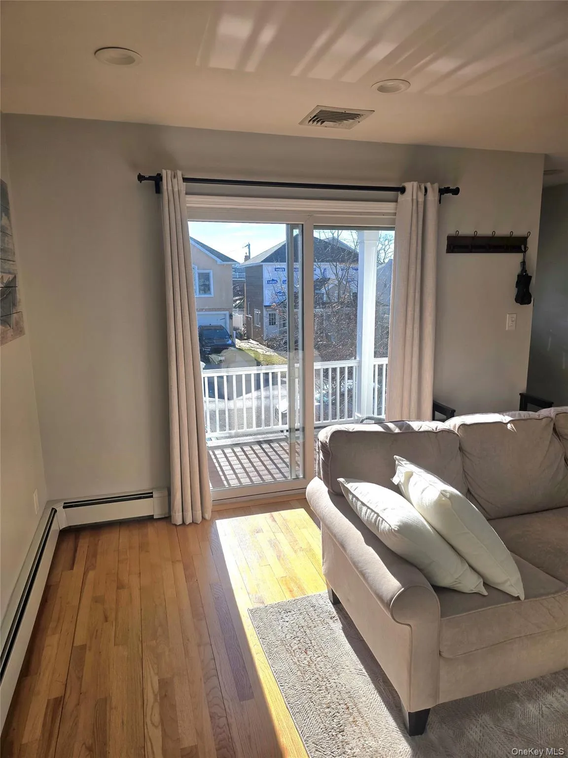 Living room featuring healthy amount of natural light, wood-type flooring, and baseboard heating Living room featuring healthy amount of natural light, wood-type flooring, and baseboard heating