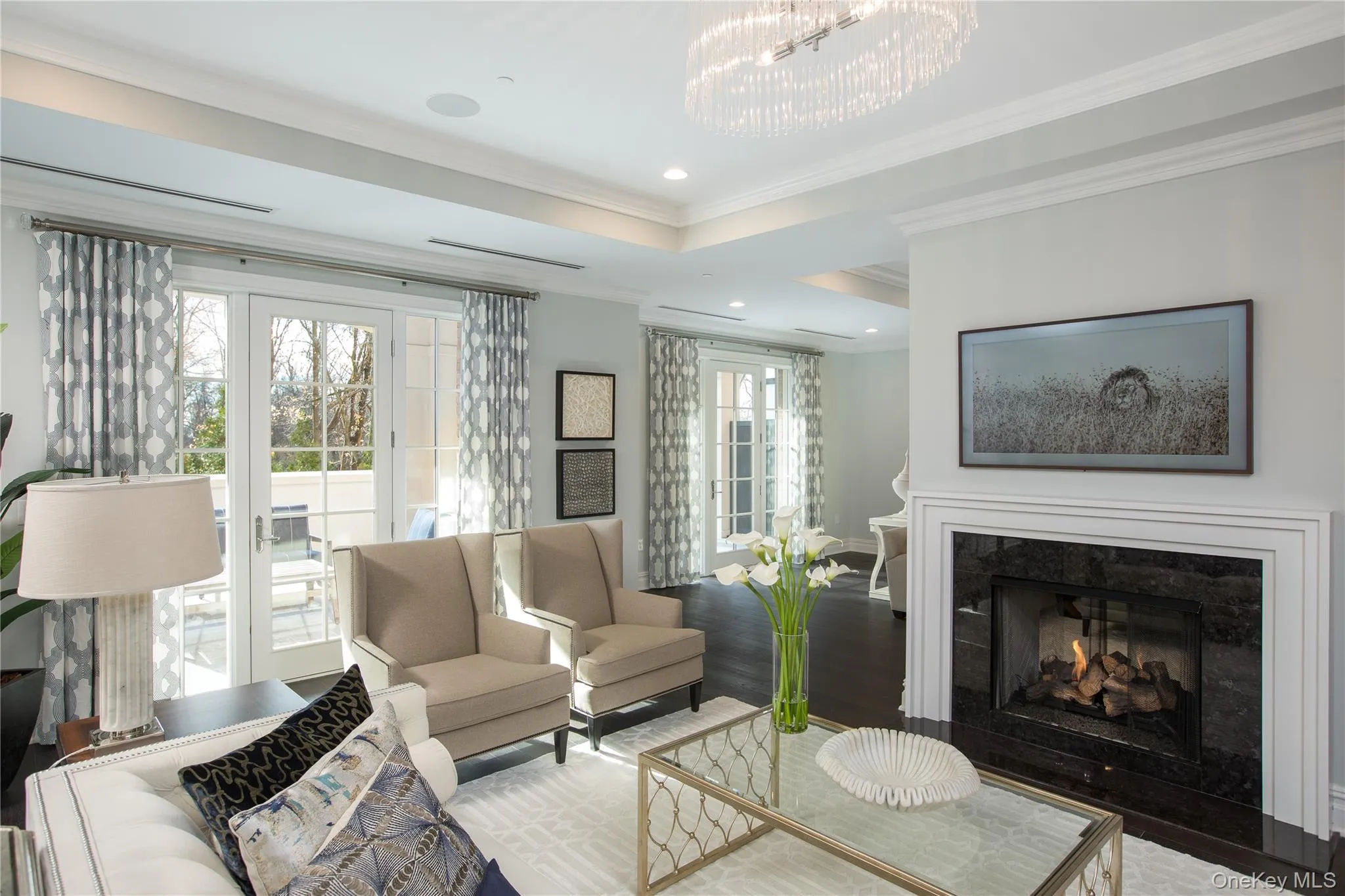 Living room with a chandelier, ornamental molding, wood finished floors, a premium fireplace, and recessed lighting Living room with a chandelier, ornamental molding, wood finished floors, a premium fireplace, and recessed lighting