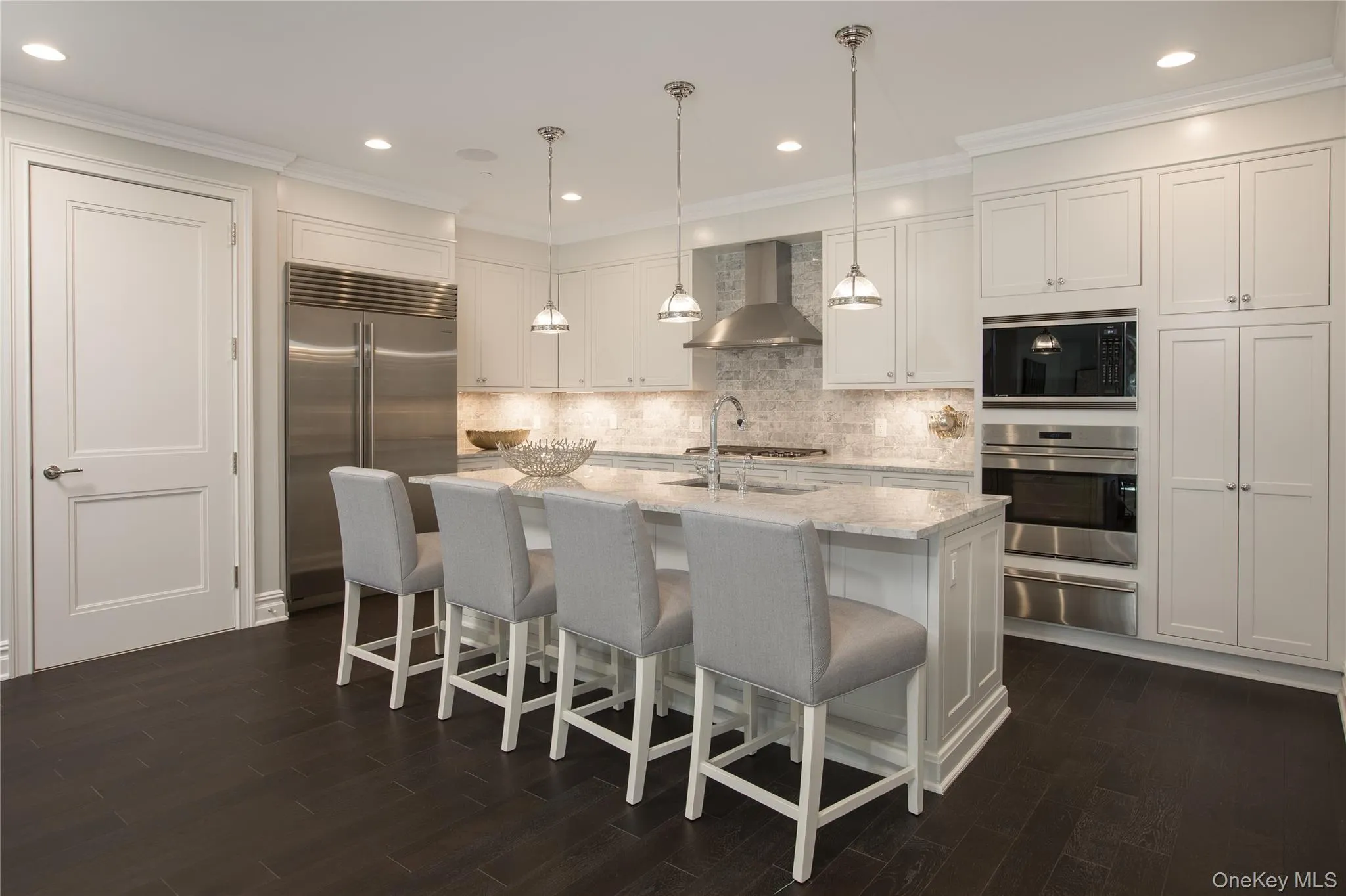 Kitchen with ornamental molding, a breakfast bar area, built in appliances, white cabinets, and recessed lighting Kitchen with ornamental molding, a breakfast bar area, built in appliances, white cabinets, and recessed lighting