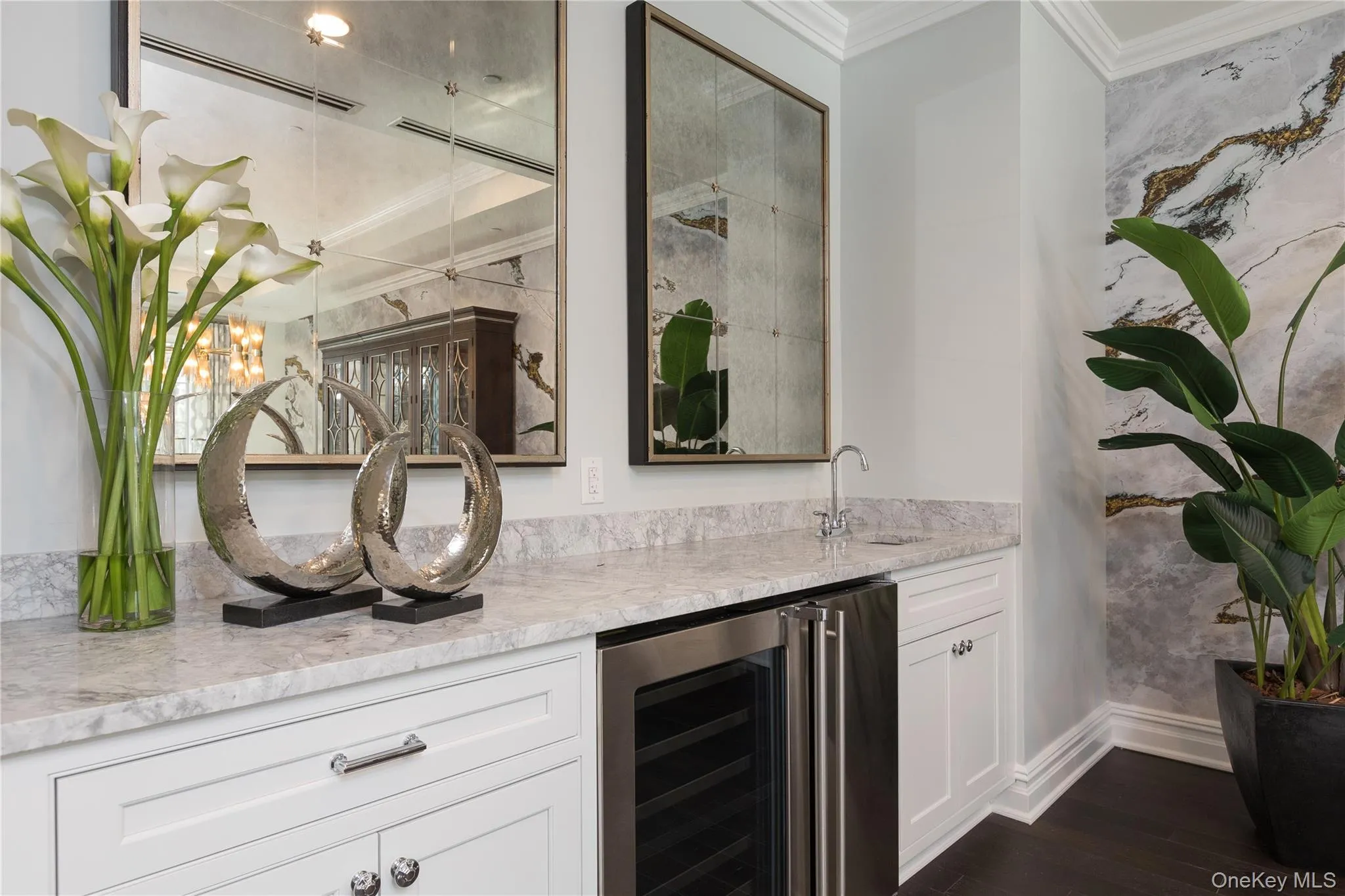 Indoor wet bar featuring white cabinetry, ornamental molding, wine cooler, light stone counters, and dark wood finished floors Indoor wet bar featuring white cabinetry, ornamental molding, wine cooler, light stone counters, and dark wood finished floors