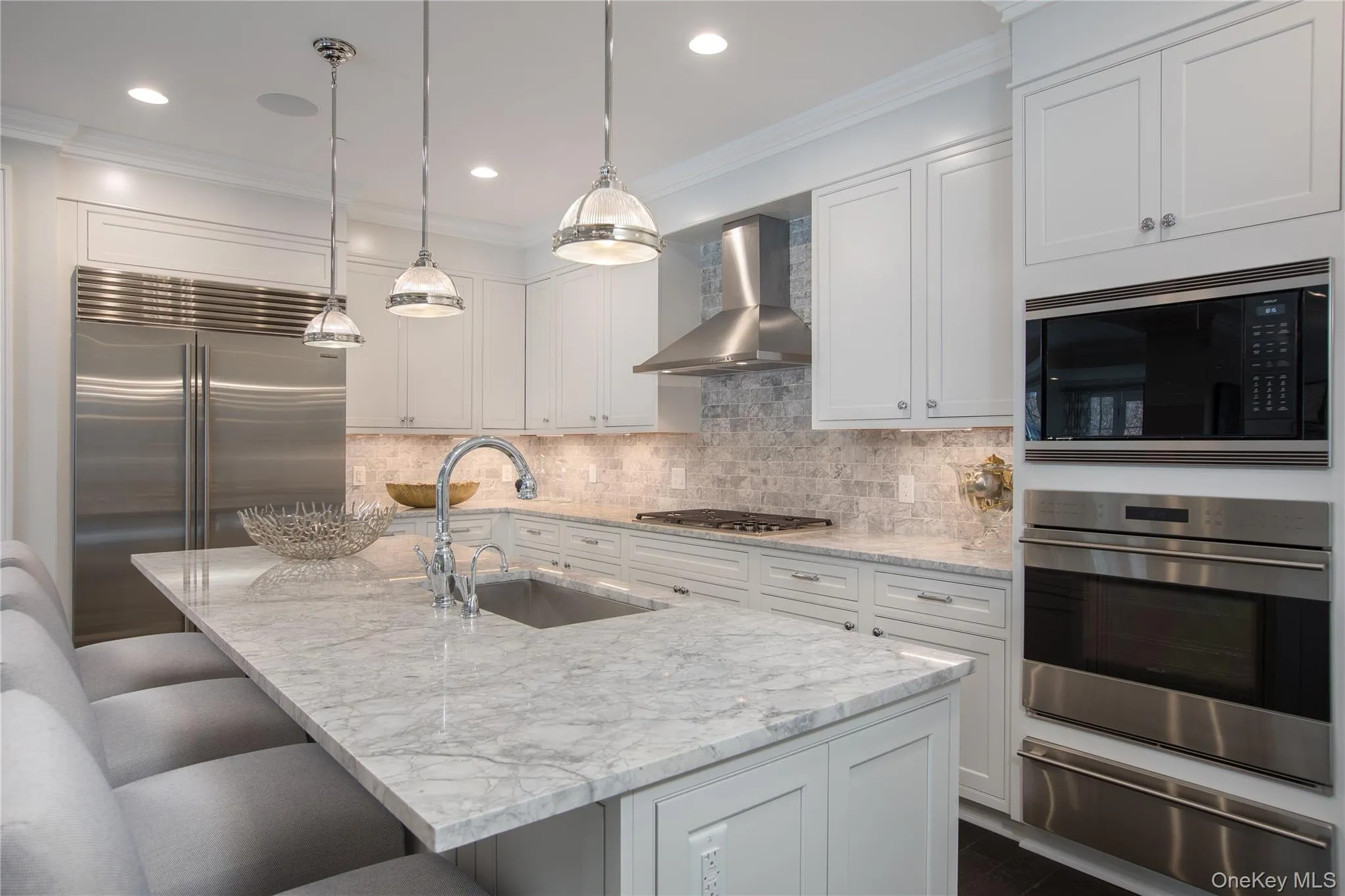 Kitchen with a warming drawer, built in appliances, crown molding, a breakfast bar, and light stone counters Kitchen with a warming drawer, built in appliances, crown molding, a breakfast bar, and light stone counters