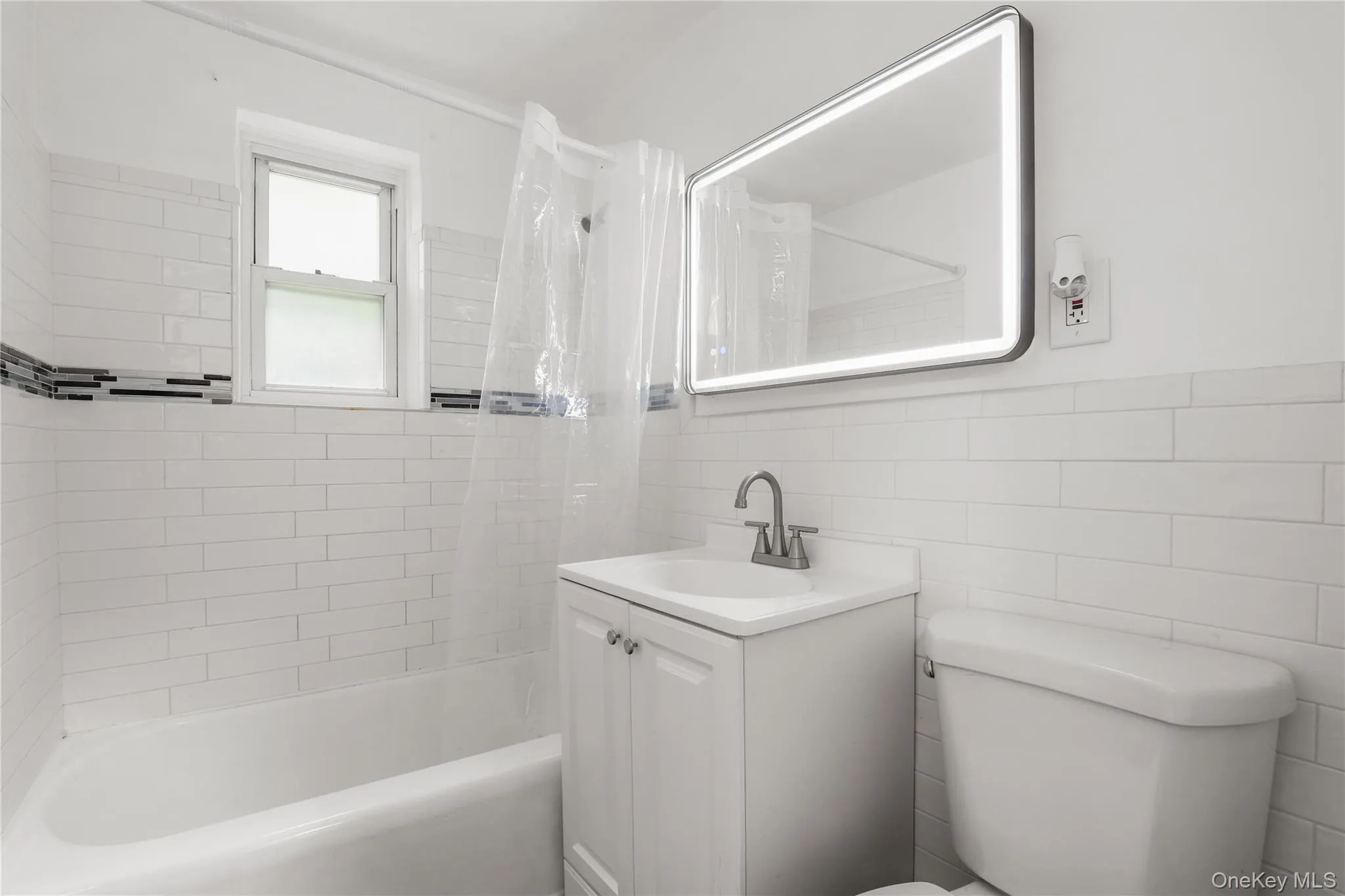 Bathroom featuring tile walls, shower / bathtub combination with curtain, and vanity Bathroom featuring tile walls, shower / bathtub combination with curtain, and vanity