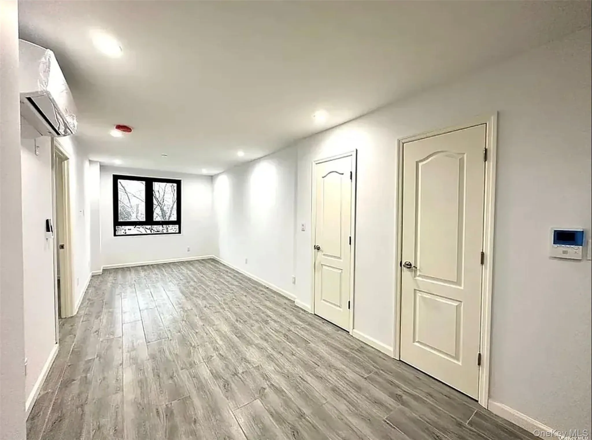 Unfurnished room featuring wood finished floors, a wall mounted air conditioner, and recessed lighting Unfurnished room featuring wood finished floors, a wall mounted air conditioner, and recessed lighting
