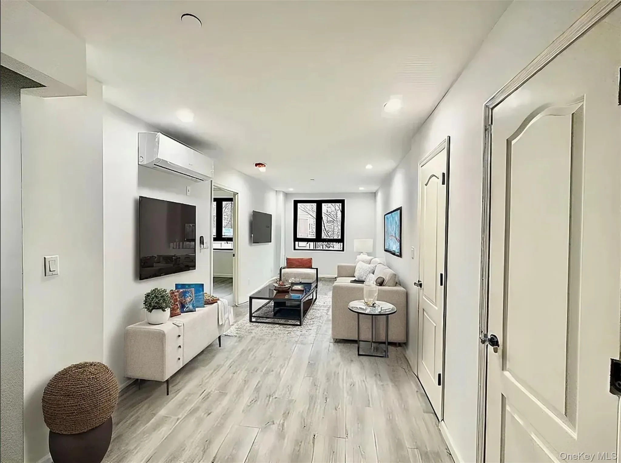 Living room with light wood-style floors, a wall mounted air conditioner, and recessed lighting Living room with light wood-style floors, a wall mounted air conditioner, and recessed lighting
