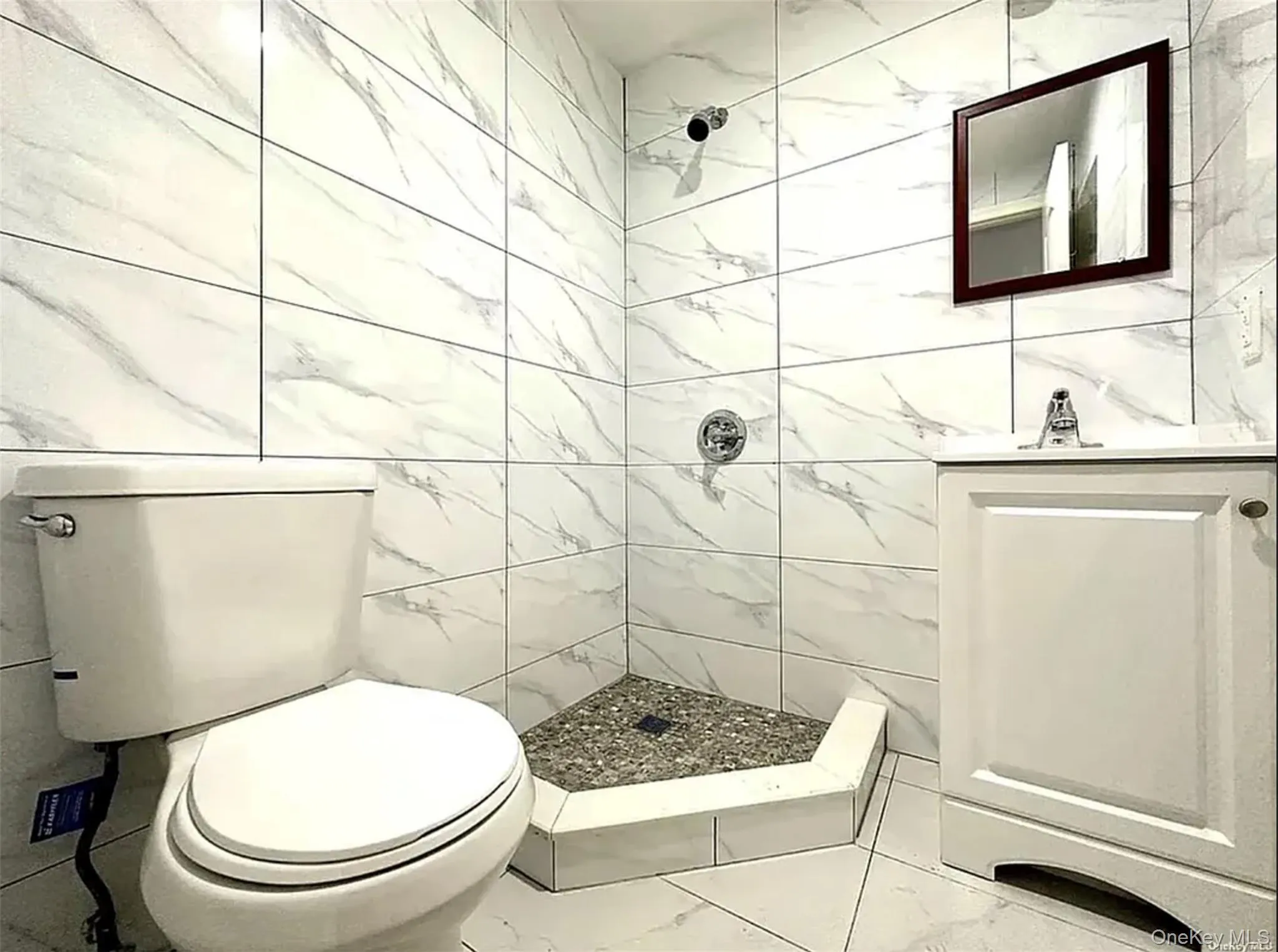 Full bathroom featuring a shower stall, vanity, tile walls, and marble look tiles Full bathroom featuring a shower stall, vanity, tile walls, and marble look tiles