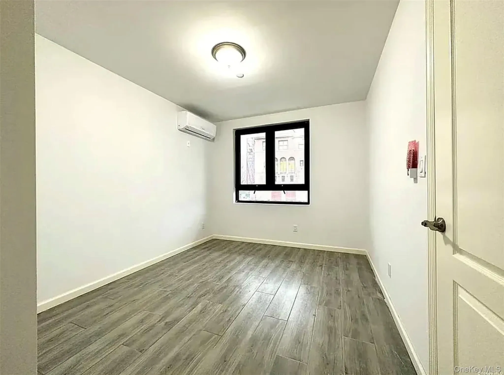 Unfurnished room featuring dark wood-type flooring and an AC wall unit Unfurnished room featuring dark wood-type flooring and an AC wall unit