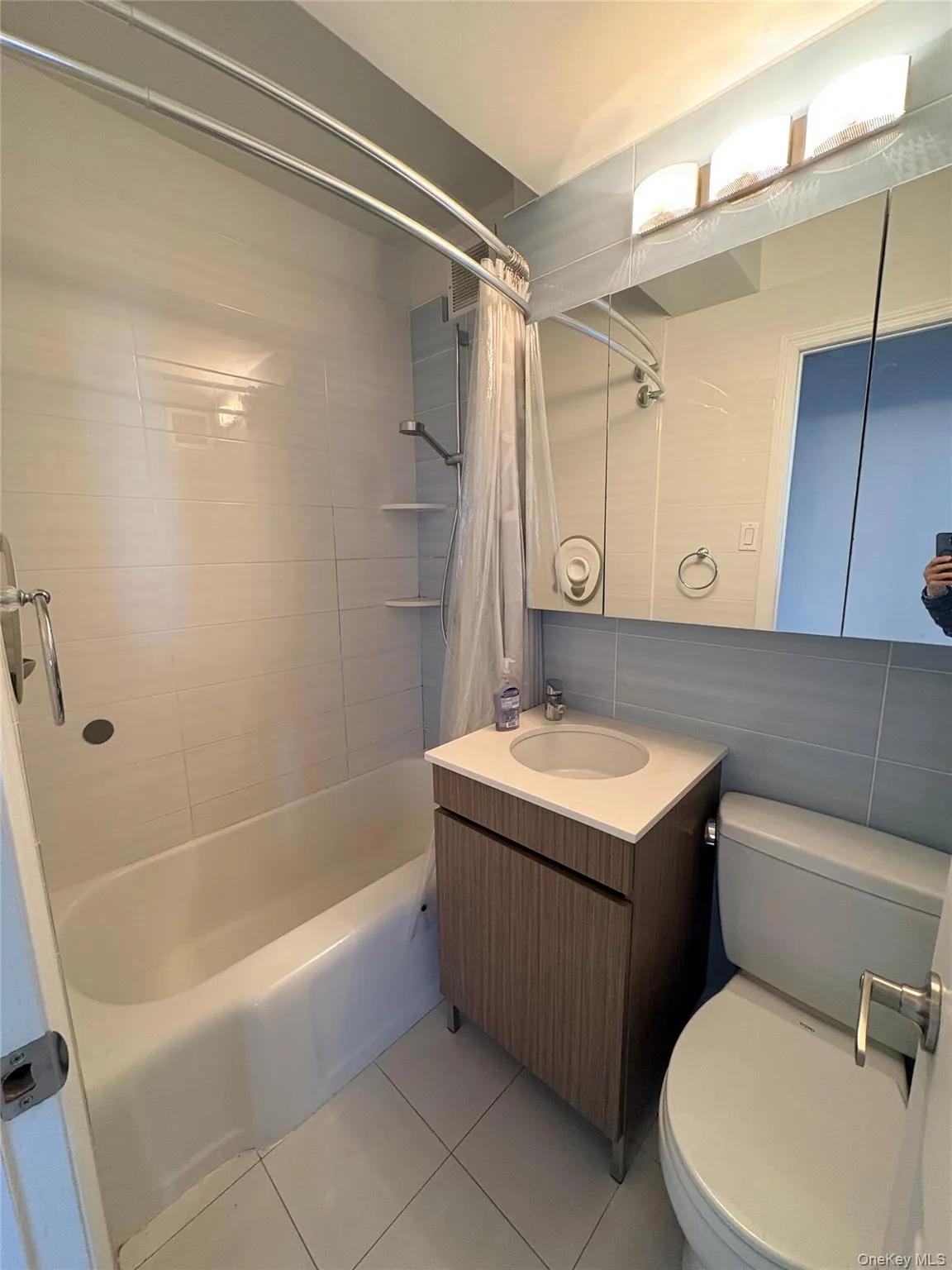 Full bathroom featuring vanity, shower / tub combo with curtain, and light tile patterned floors Full bathroom featuring vanity, shower / tub combo with curtain, and light tile patterned floors
