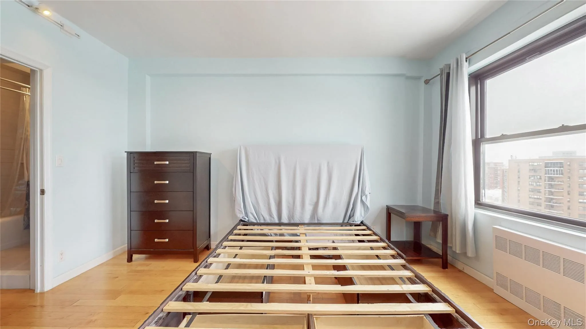 Bedroom featuring radiator heating unit and light wood-style floors Bedroom featuring radiator heating unit and light wood-style floors