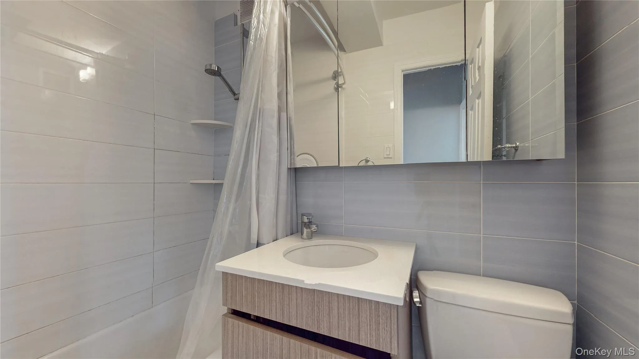 Full bathroom featuring vanity, tile walls, and shower / bath combo with shower curtain Full bathroom featuring vanity, tile walls, and shower / bath combo with shower curtain
